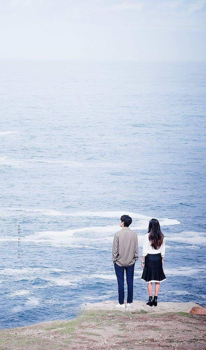 Korean Couple Standing Near The Ocean Background