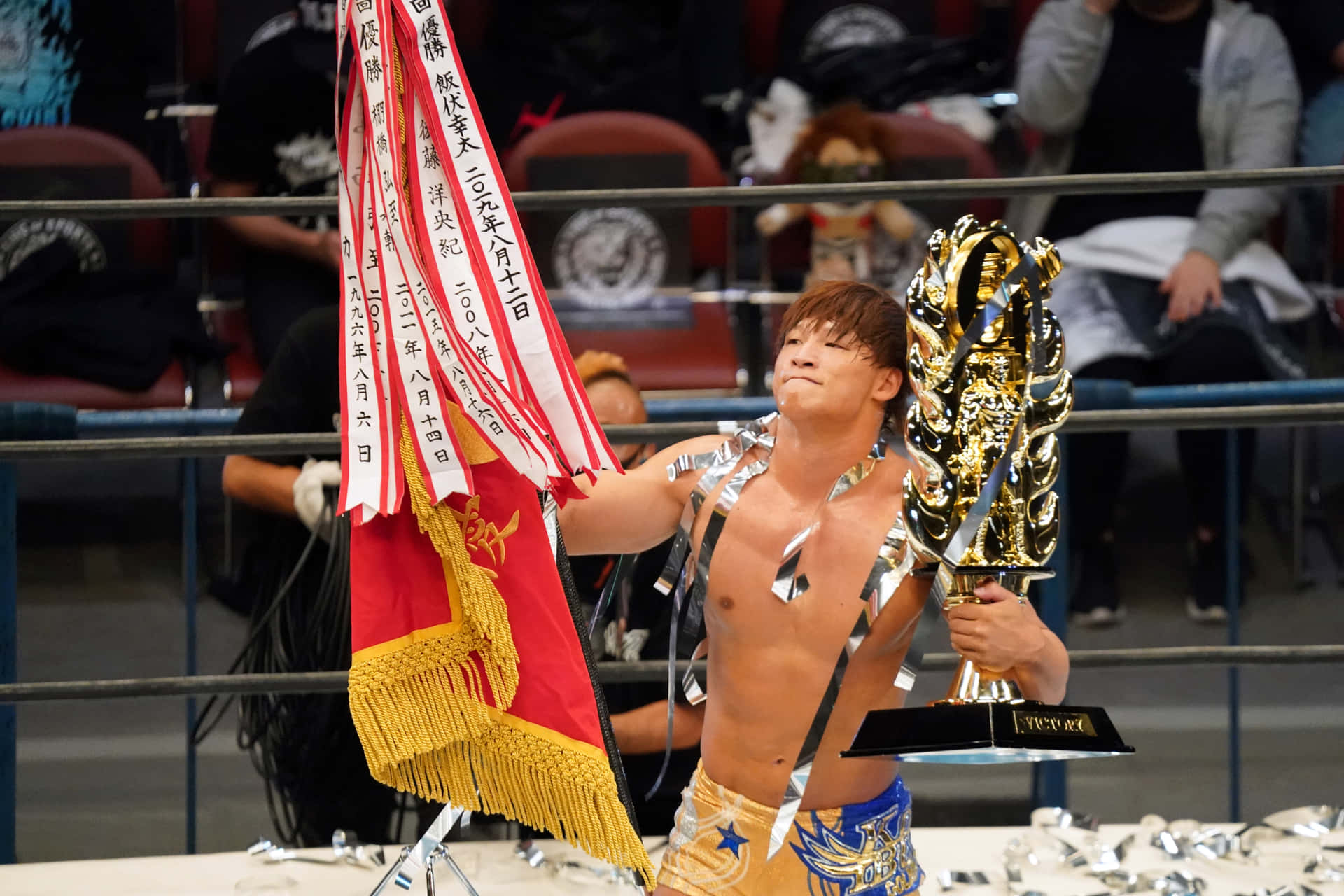 Kota Ibushi Holding The Trophy At G1 Climax Background