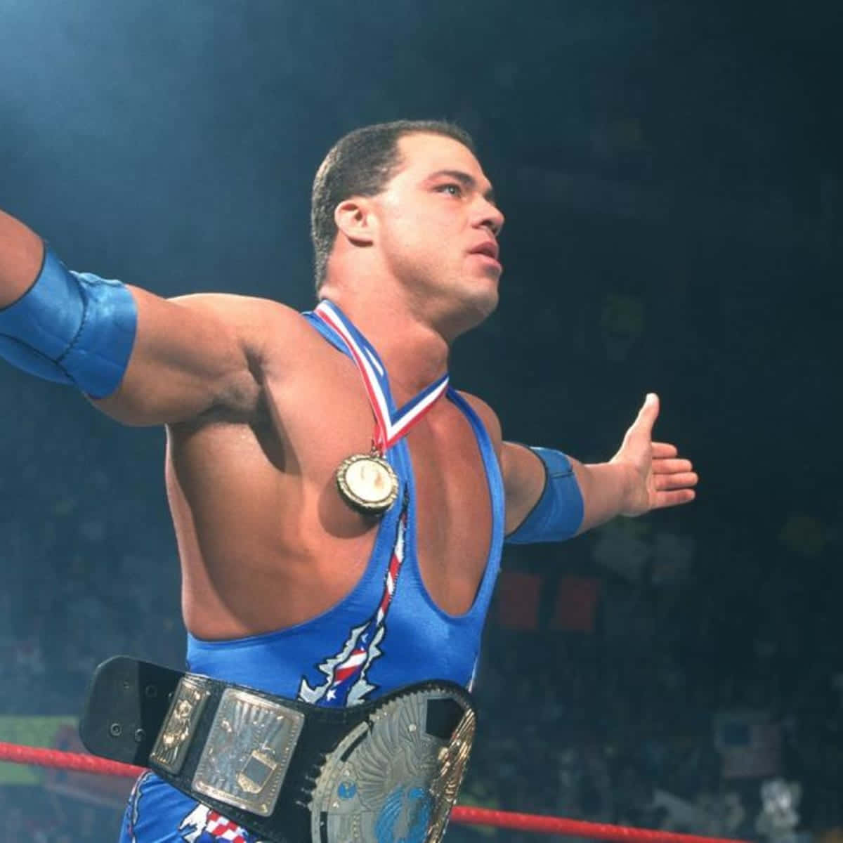 Kurt Angle Poses In Blue Singlet With Championship Belt Background