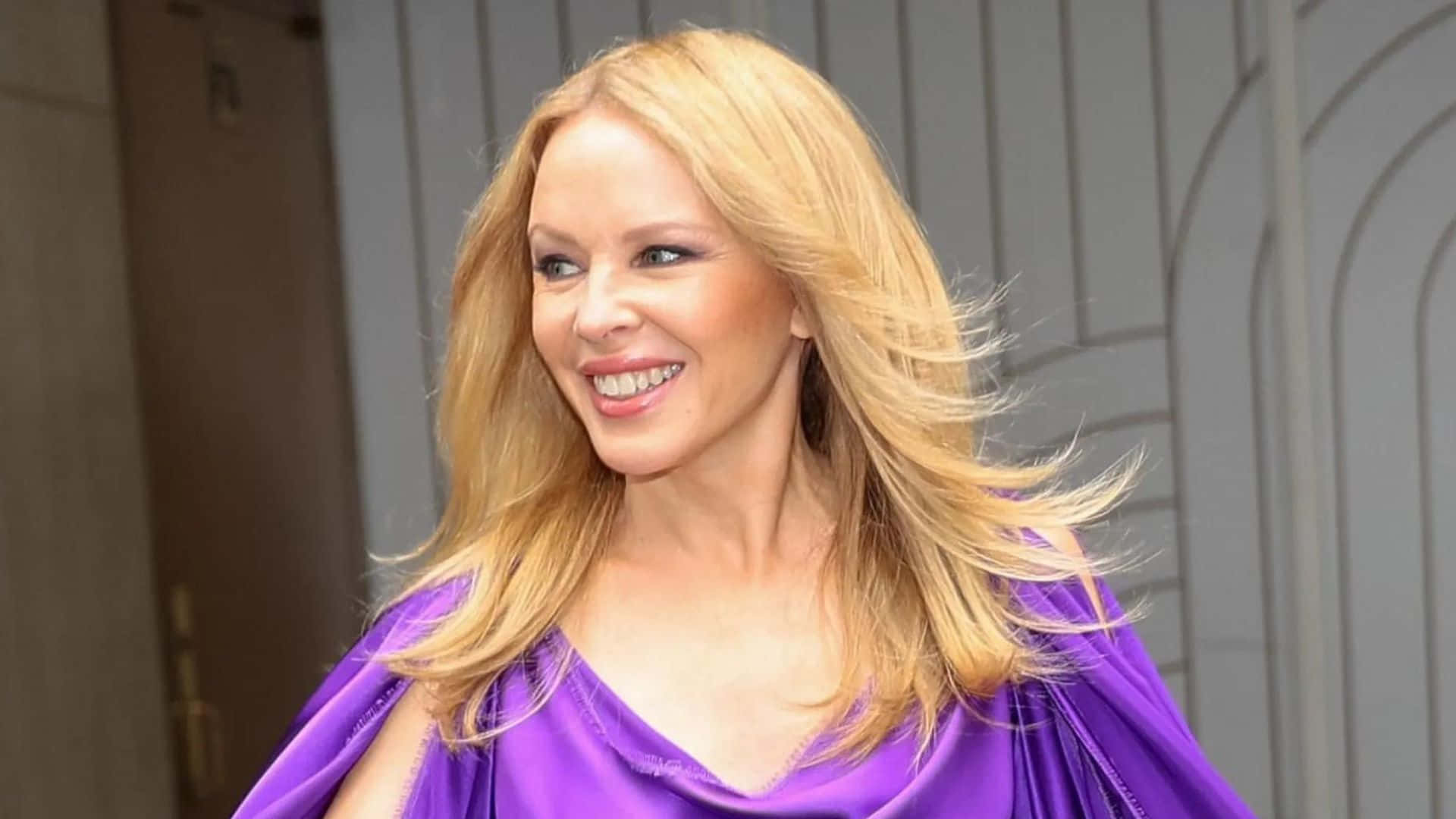 Kylie Minogue Smilingin Purple Dress Background