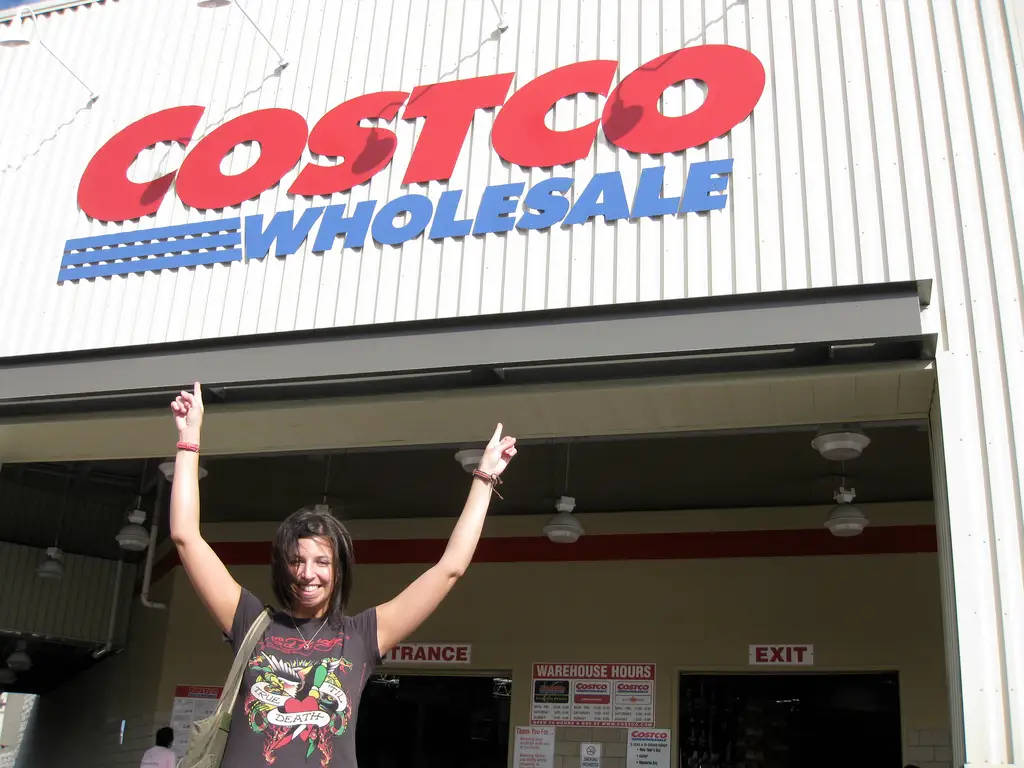 Lady Pointing To Costco Signage Background