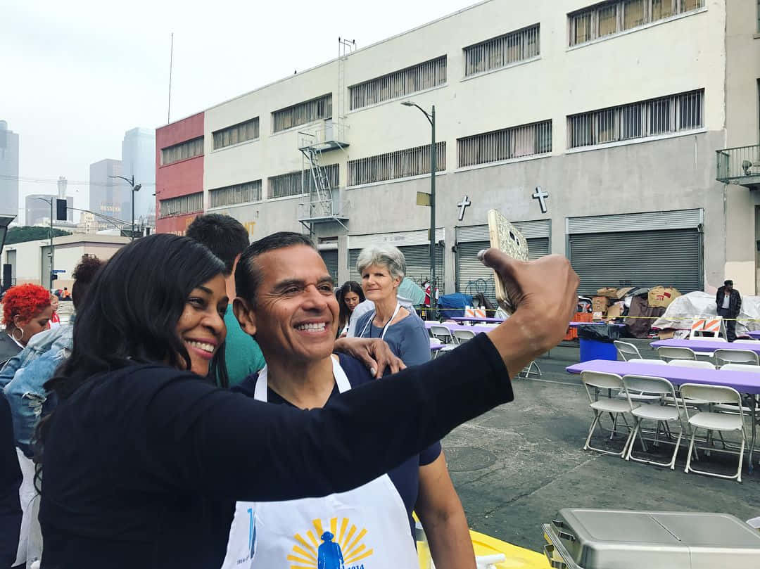 Lady Taking Selfie With Antonio Villaraigosa Background