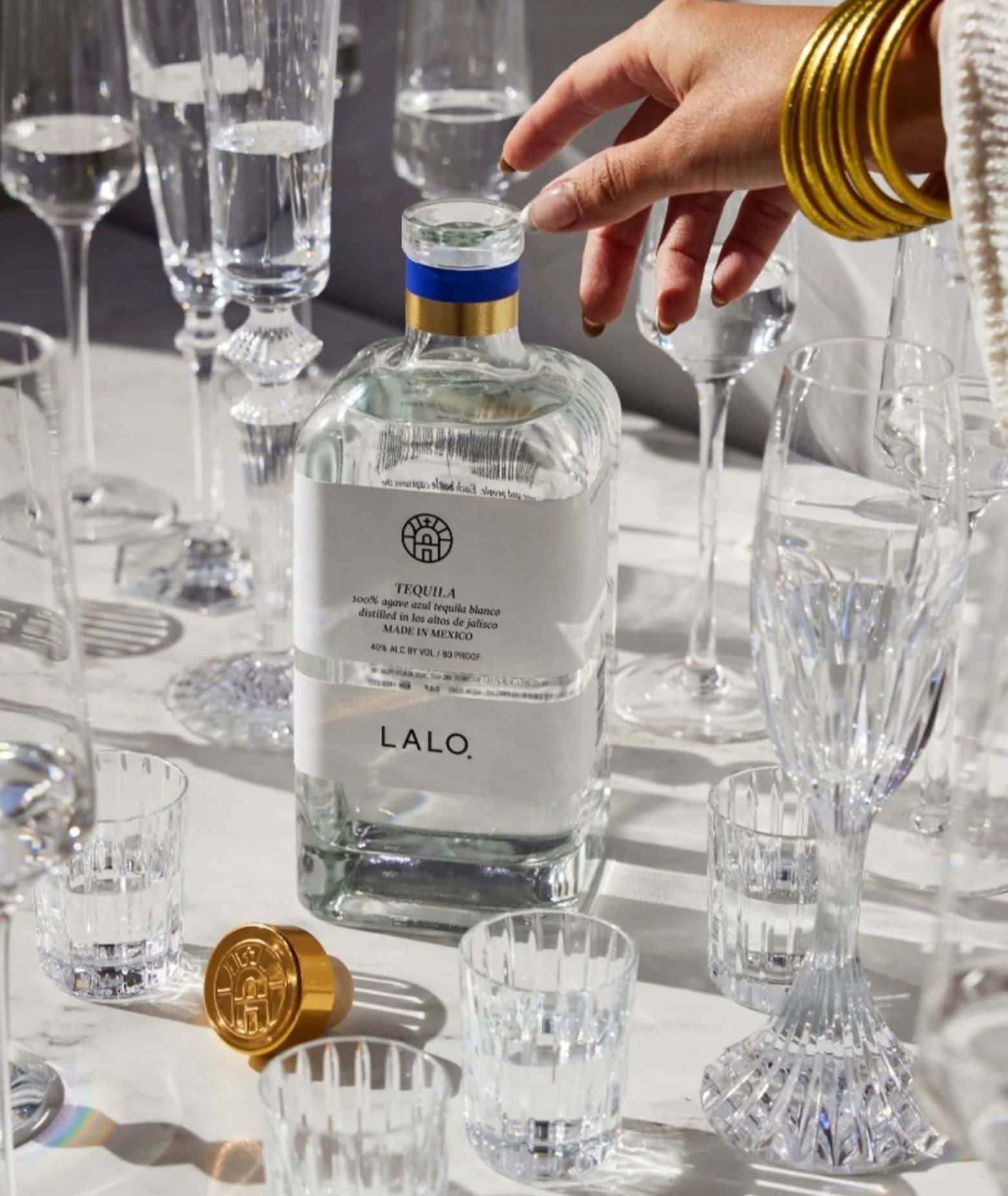 Lalo Tequila Bottle Among Crystal Glasses Background