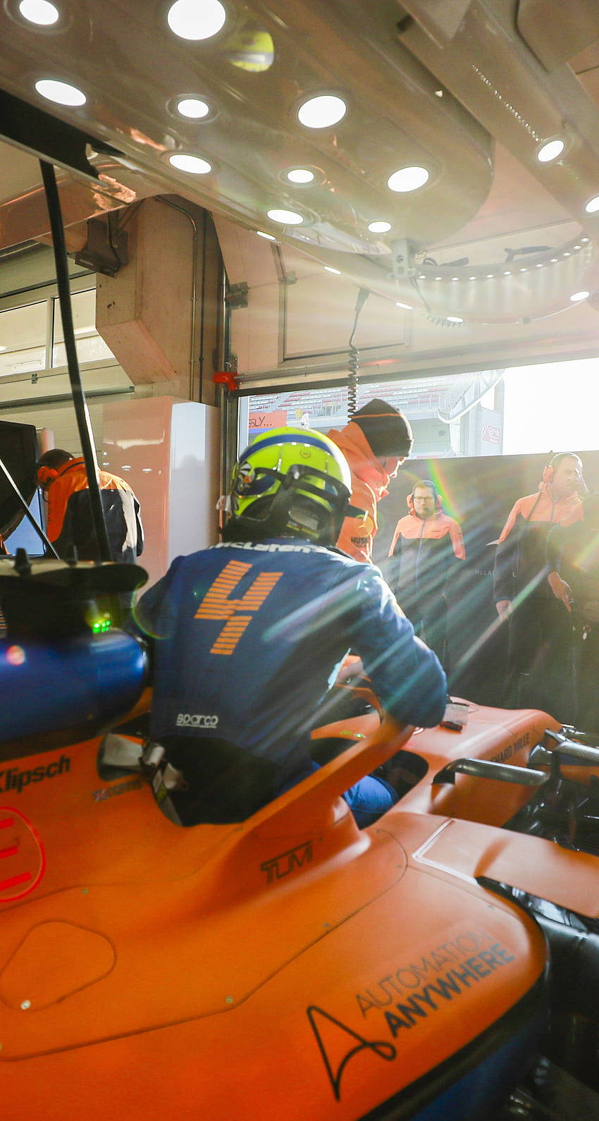 Lando Norris In Mclaren F1- Lando Norris Speeding In His Vibrant Orange Mclaren Formula 1 Car During A Race. Background