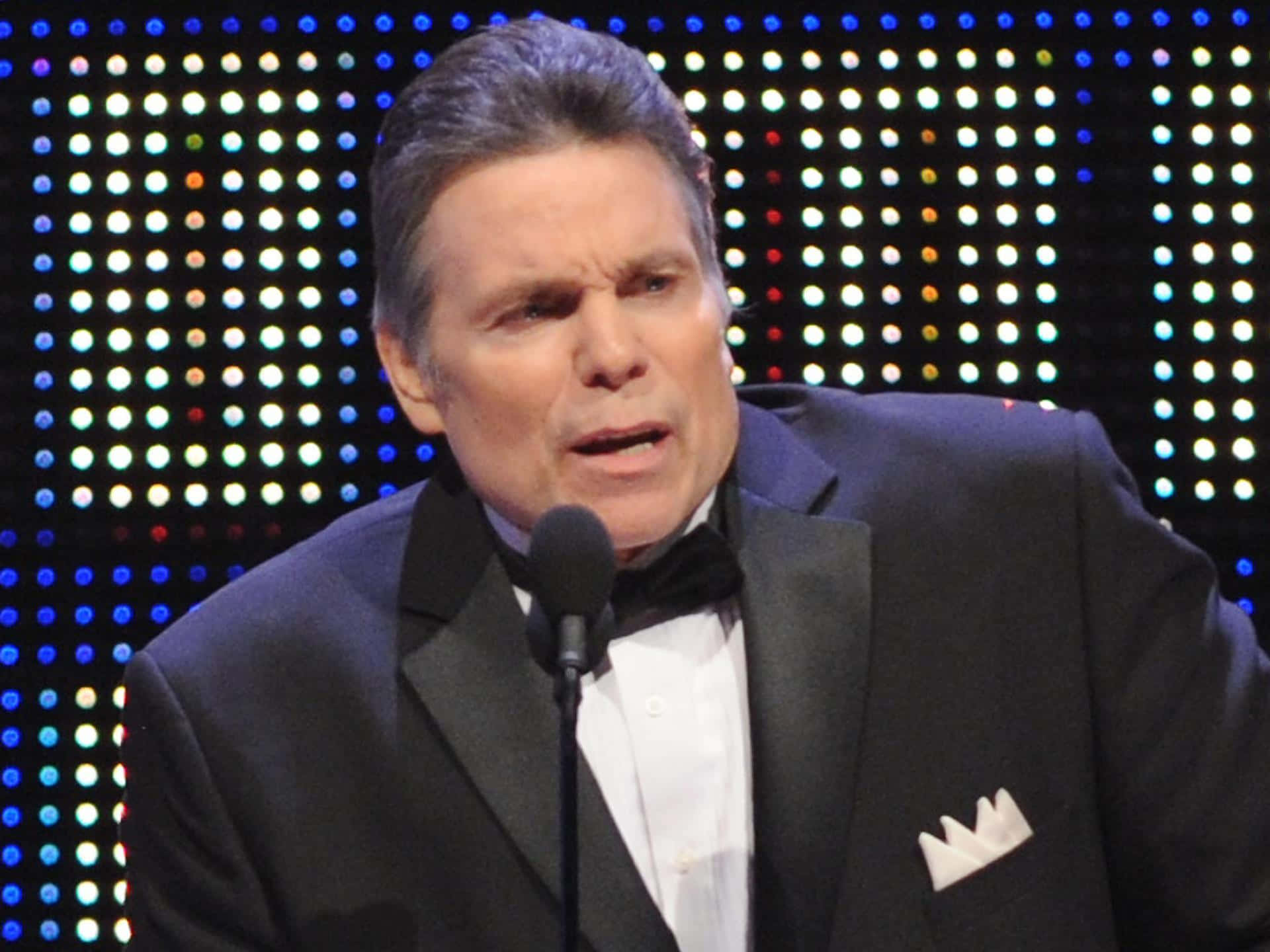 Lanny Poffo Holds A Microphone During An Interview Background