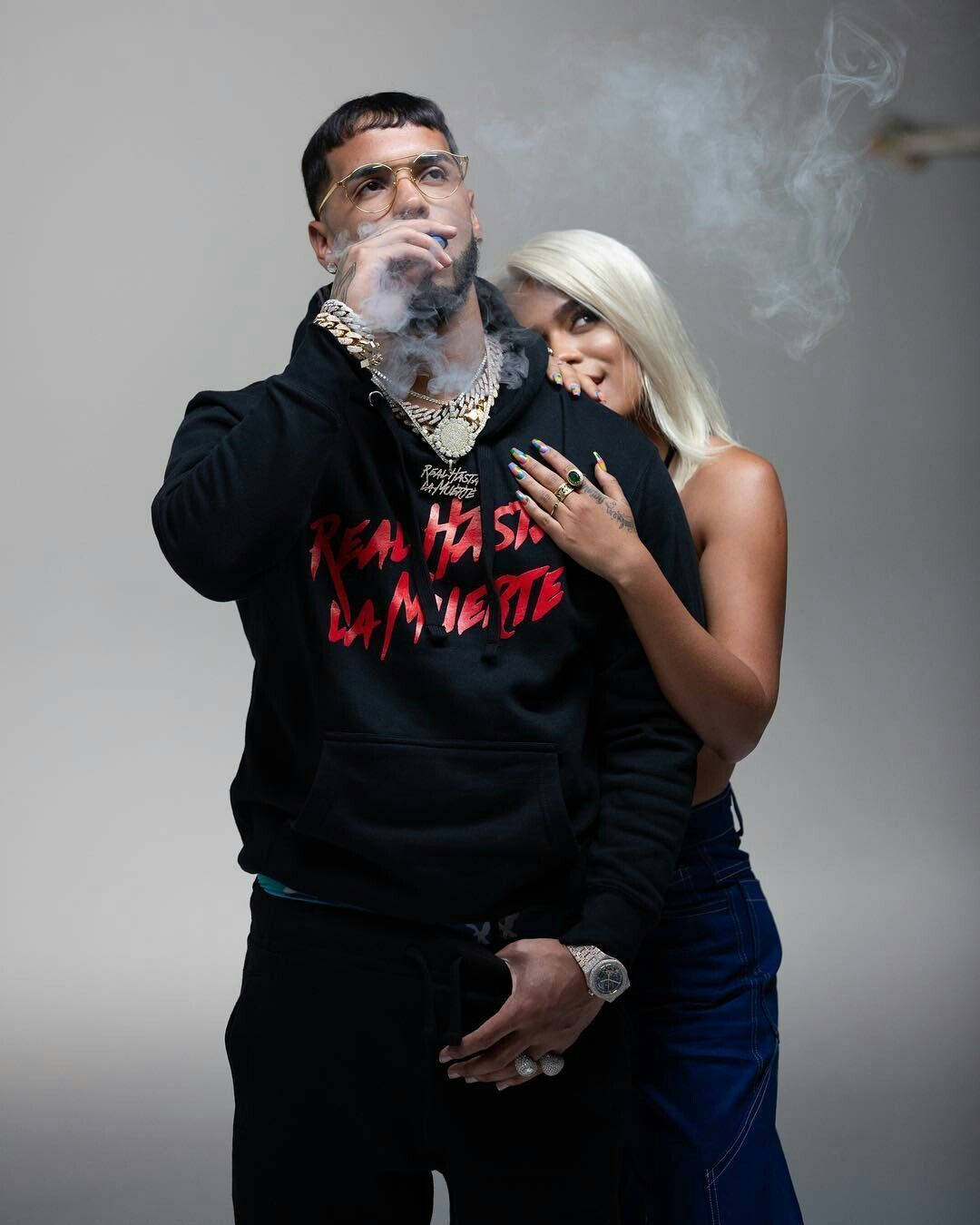 Latino Rapper Anuel Aa With Karol G Background