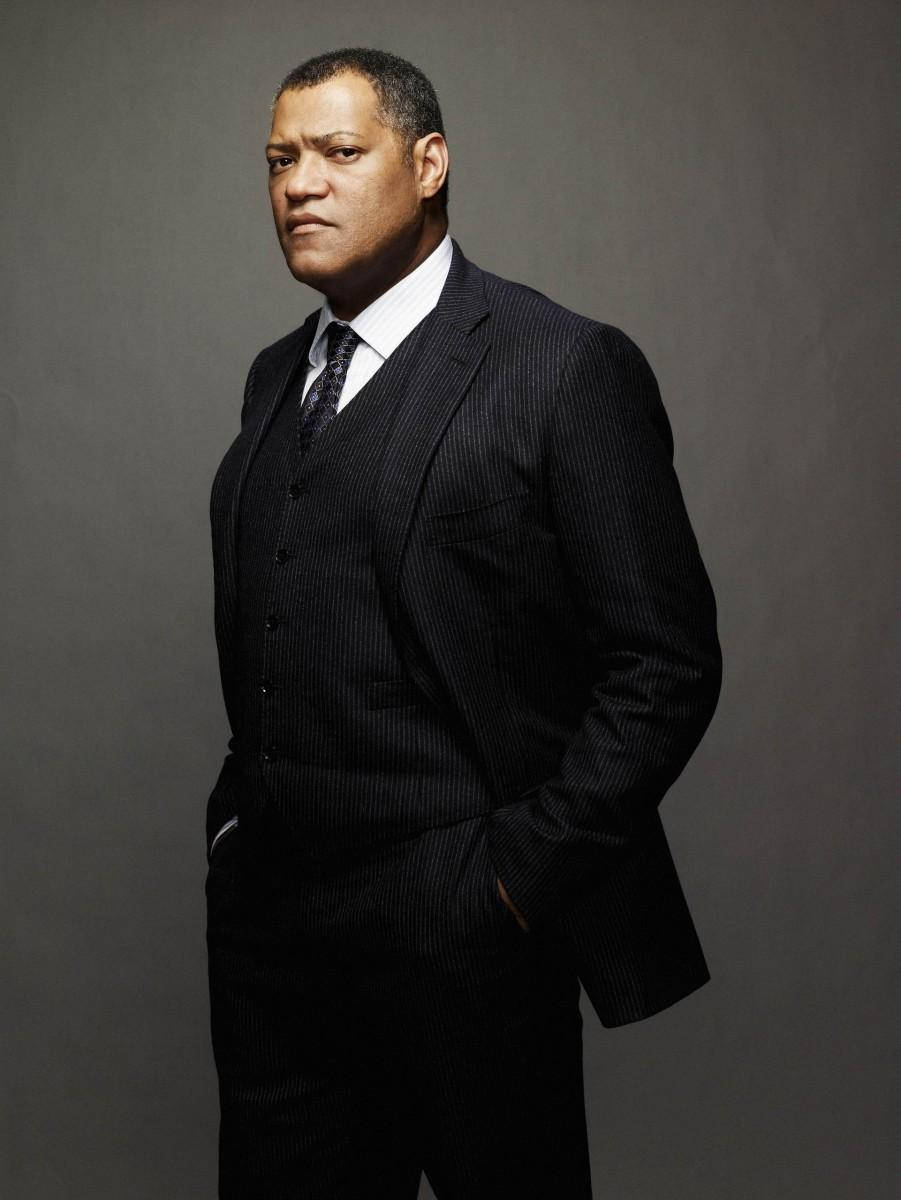 Laurence Fishburne In Casual Attire Standing-confidently With His Hands In His Pockets Background