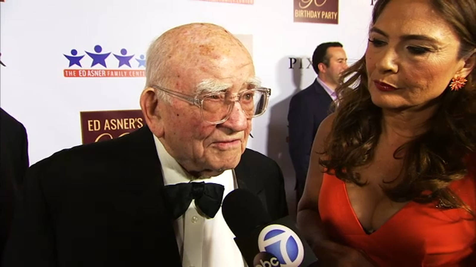 Legendary Actor Edward Asner Engaging In A Friendly Conversation With A Reporter Background