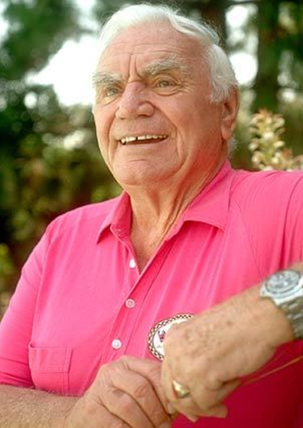 Legendary Actor Ernest Borgnine Smiling In A Pink Shirt Background