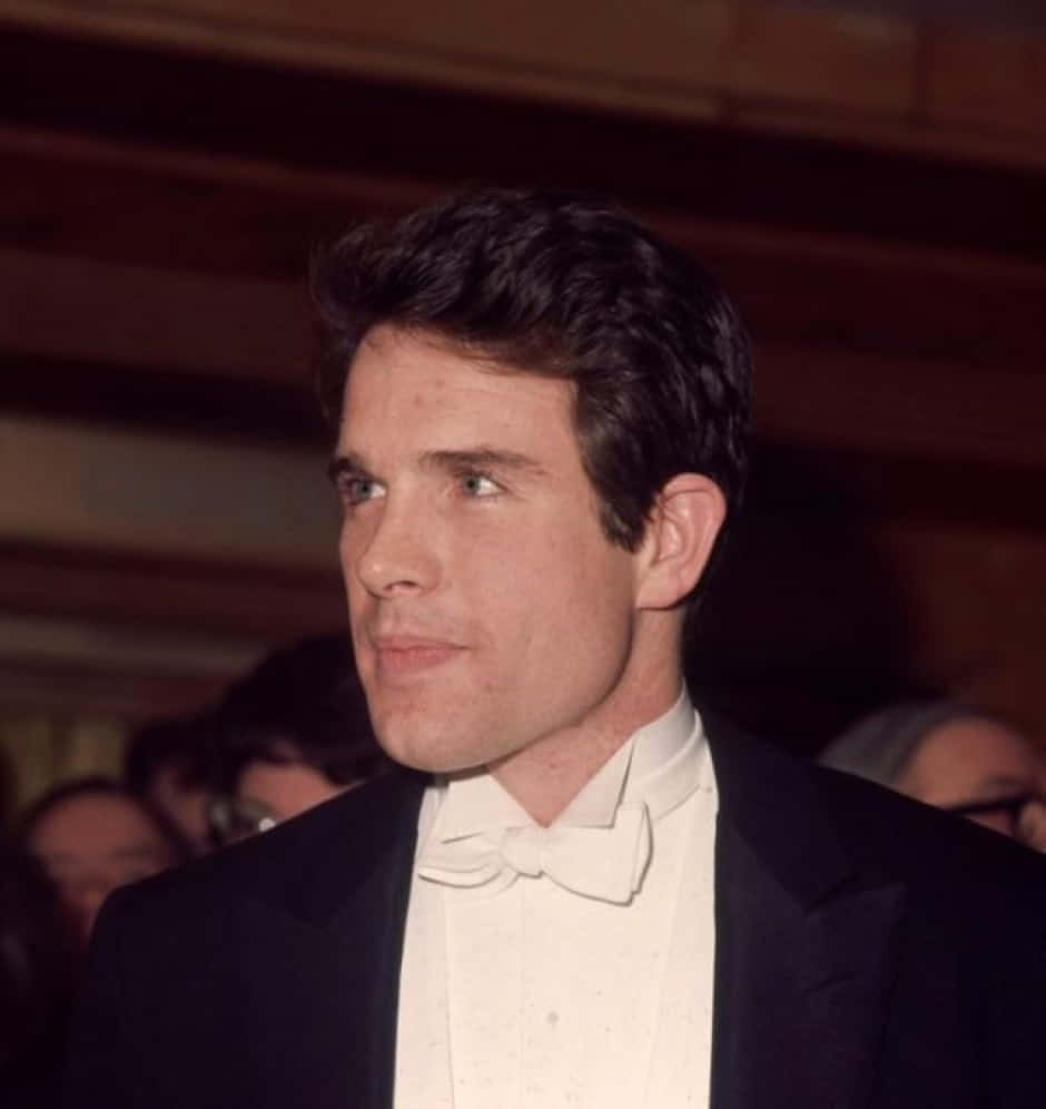 Legendary Actor Warren Beatty Smiling In A Classic Black Suit Background