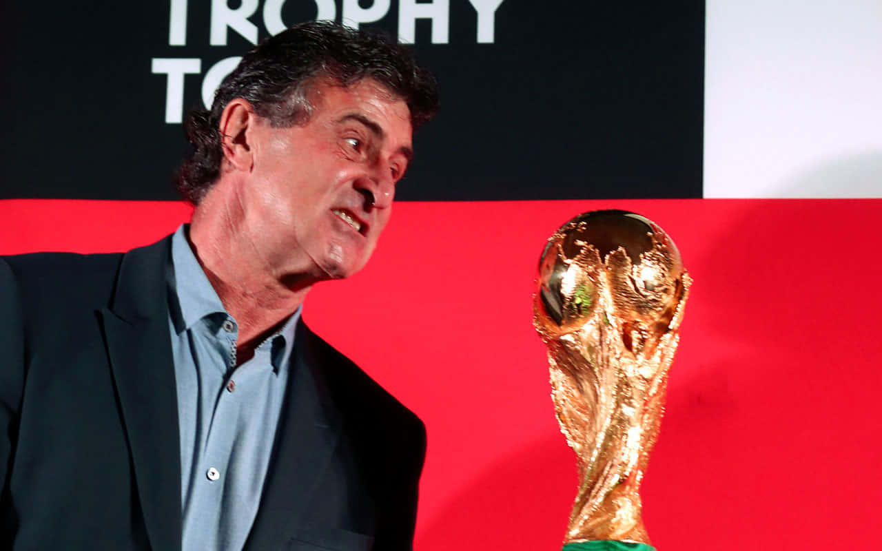 Legendary Footballer Mario Kempes Holding Fifa World Cup Trophy Background