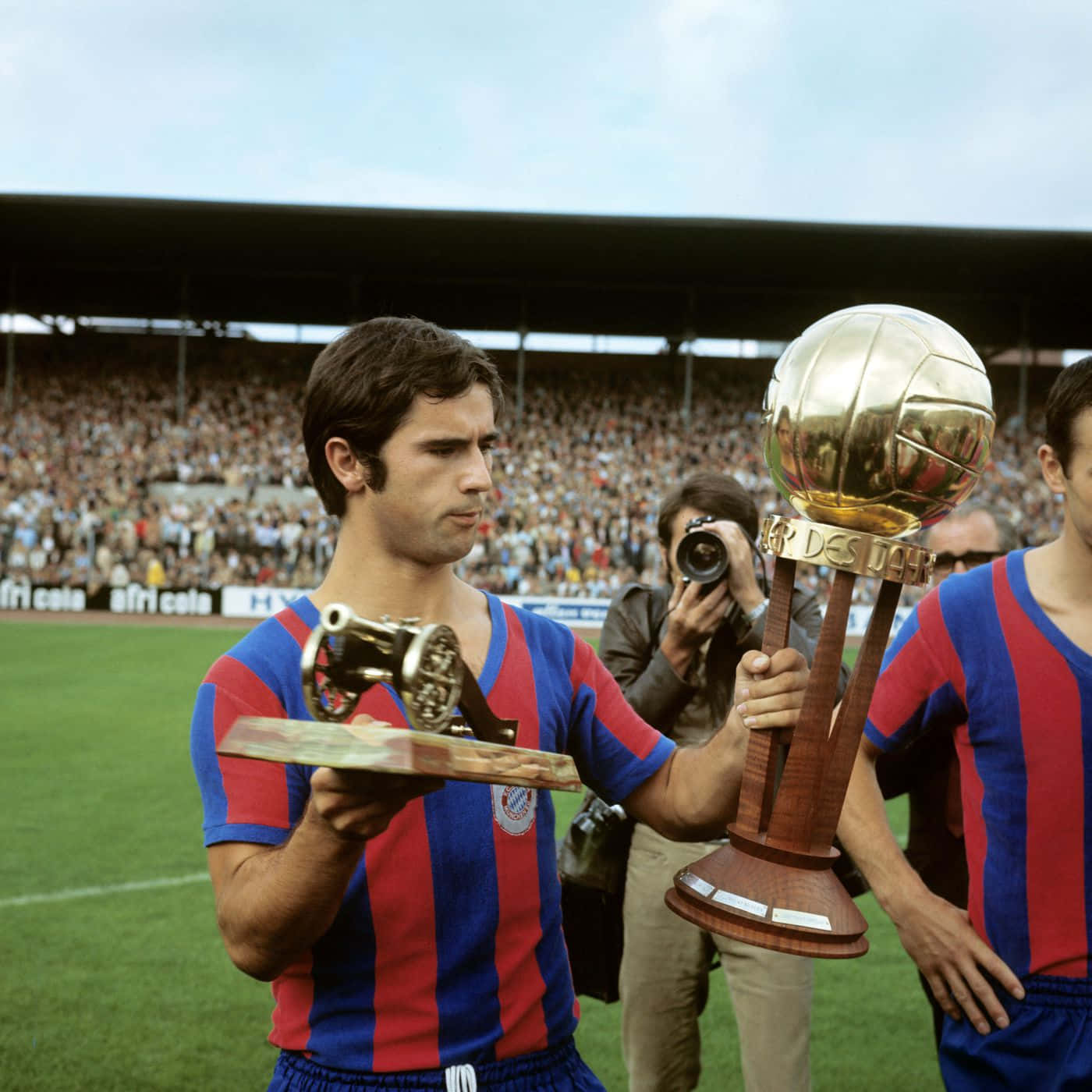 Legendary German Footballer Gerd Muller Triumphantly Holding Two Trophies
