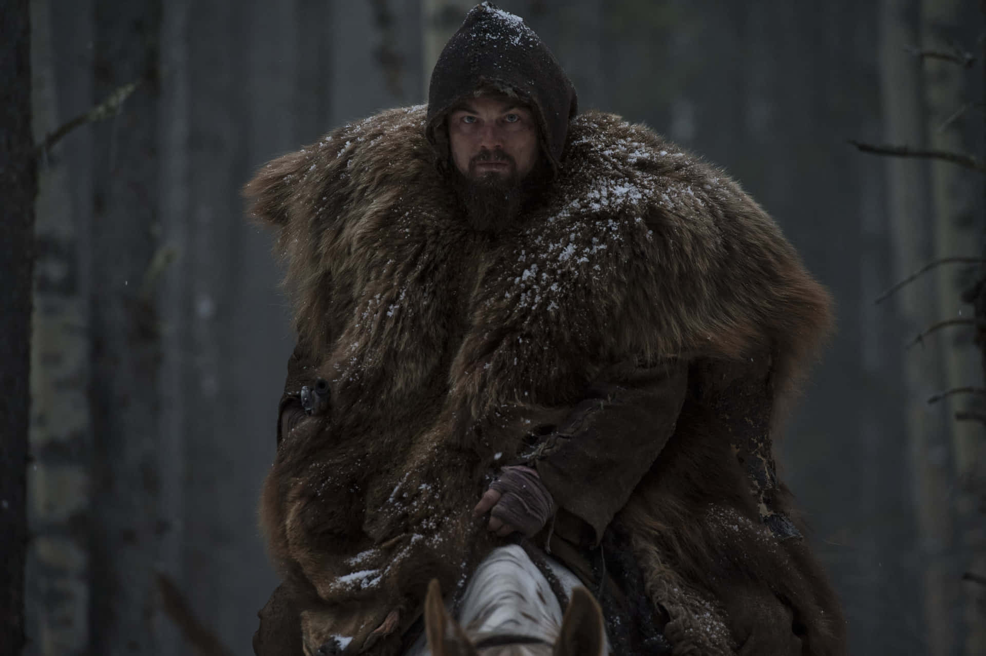 Leonardo Dicaprio In The Revenant Trudging Through Snowy Wilderness Background