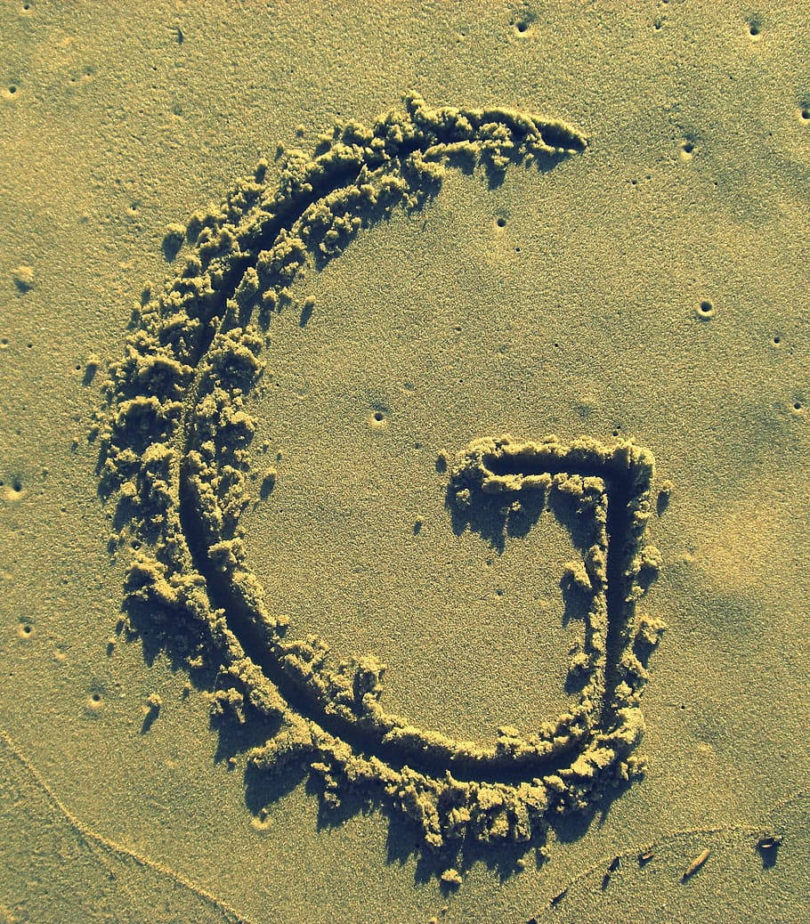 Letter G In The Sand Background
