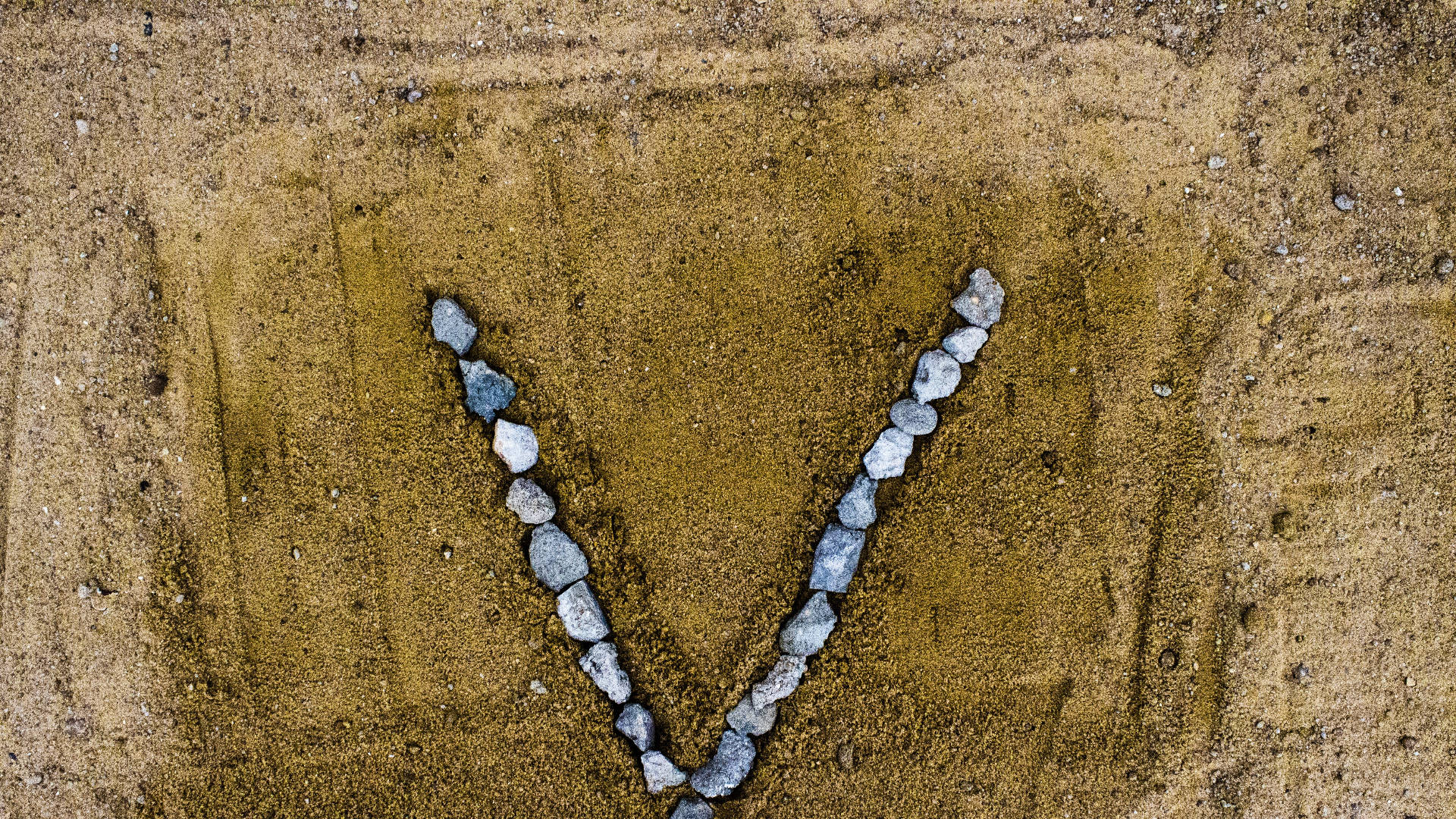 Letter V Shaped Rocks On Sand Background