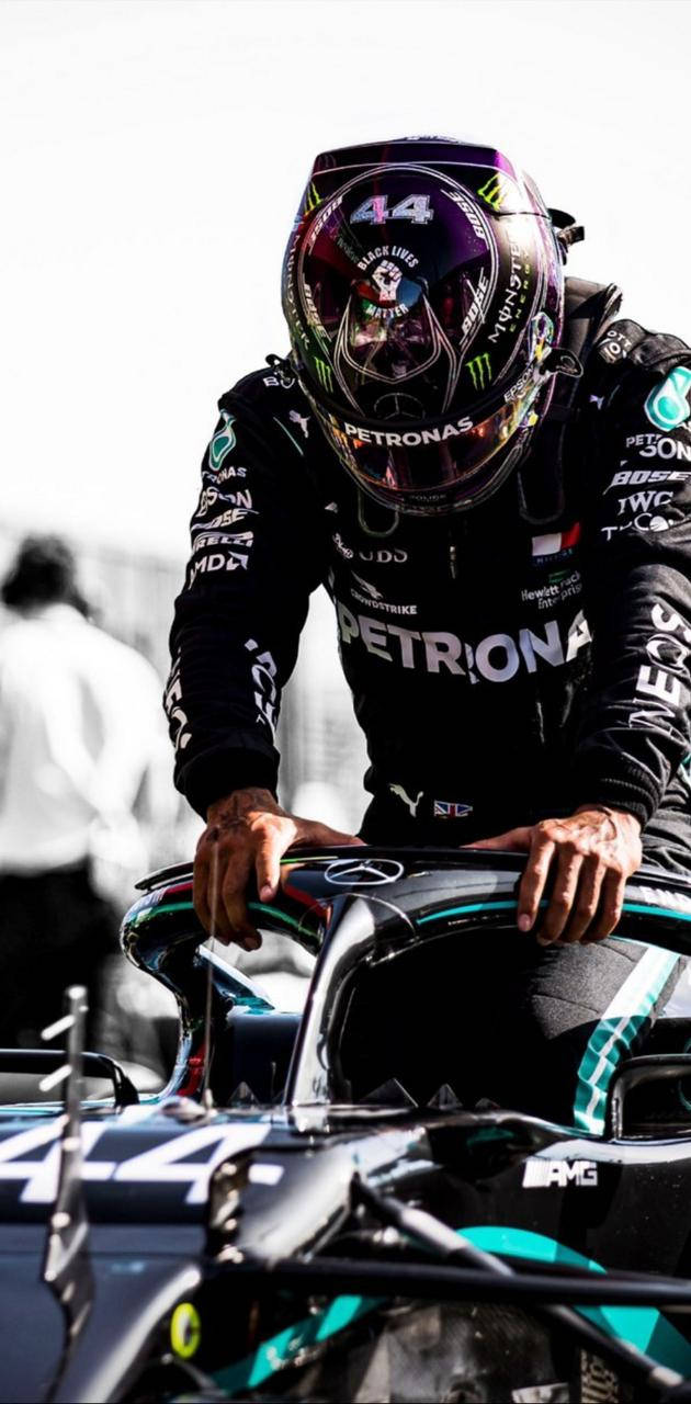 Lewis Hamilton F1 About To Sit On His Racing Car Background