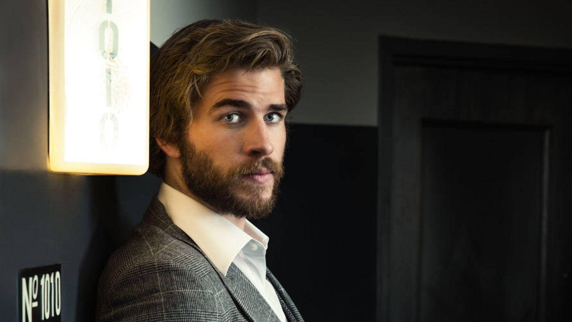 Liam Hemsworth Leaning On Wall Background