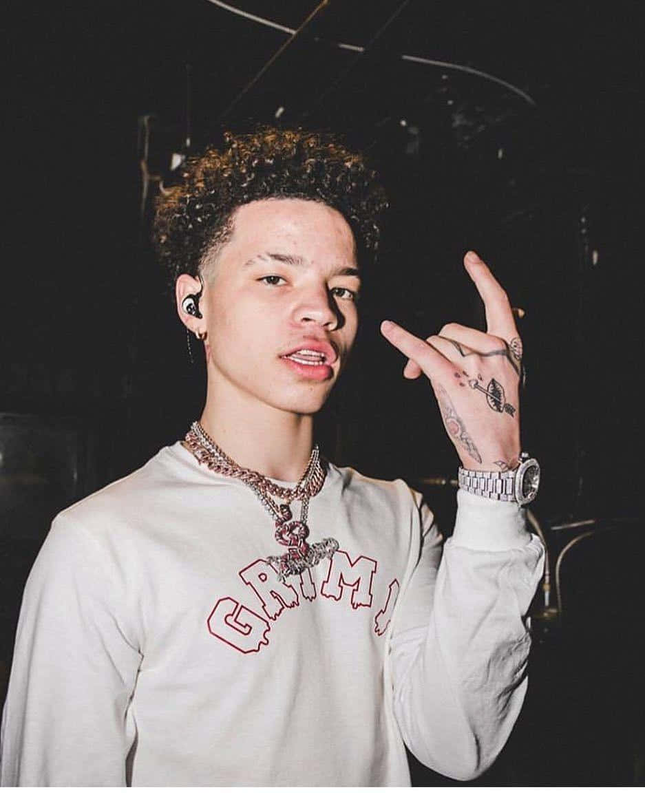 Lil Mosey Dressed In A Bright Yellow Jacket And Pants, Standing Confidently In Front Of A Grey Background.