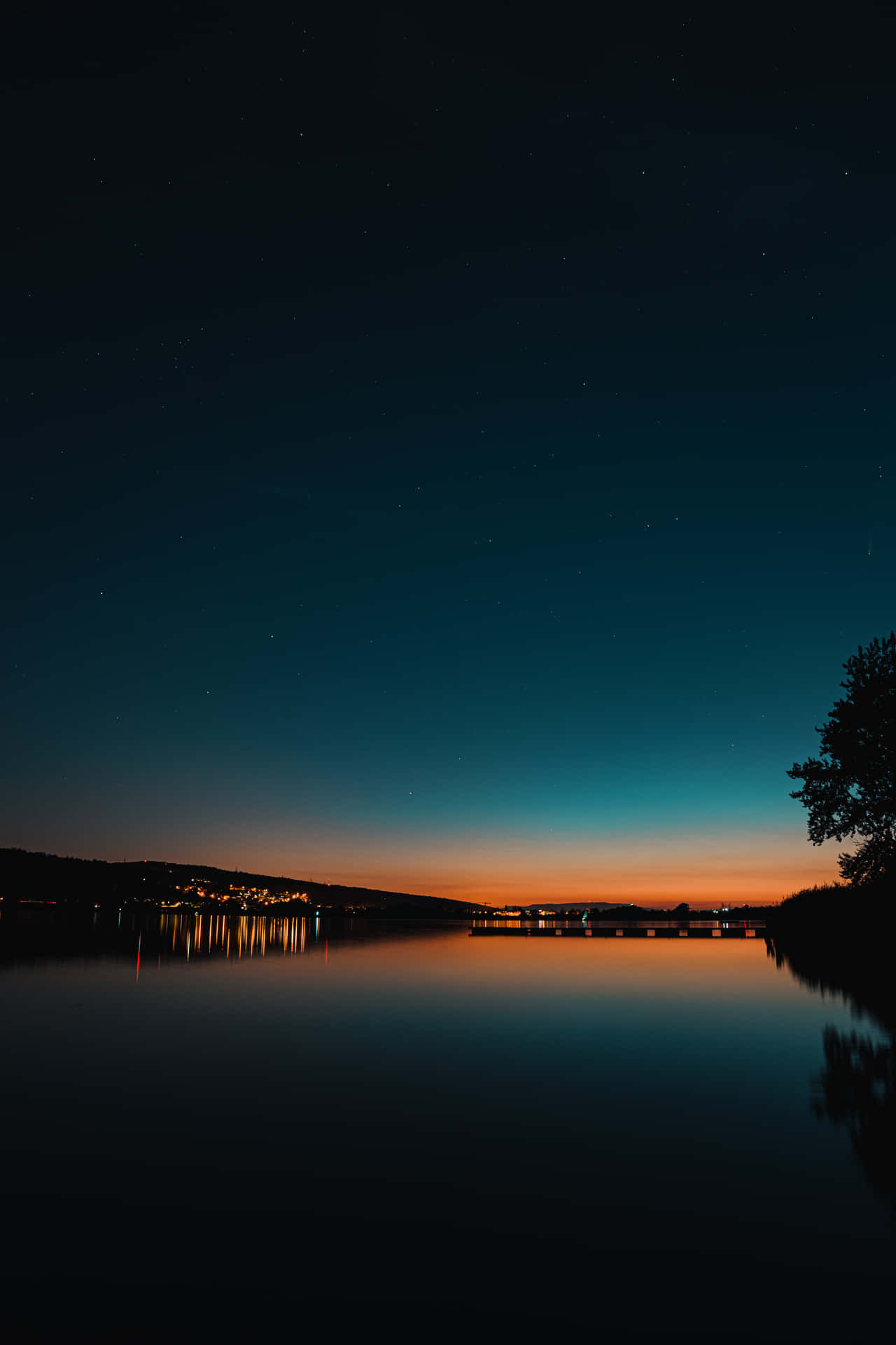 Lit Buildings Near Lake Under Starry Evening Sky