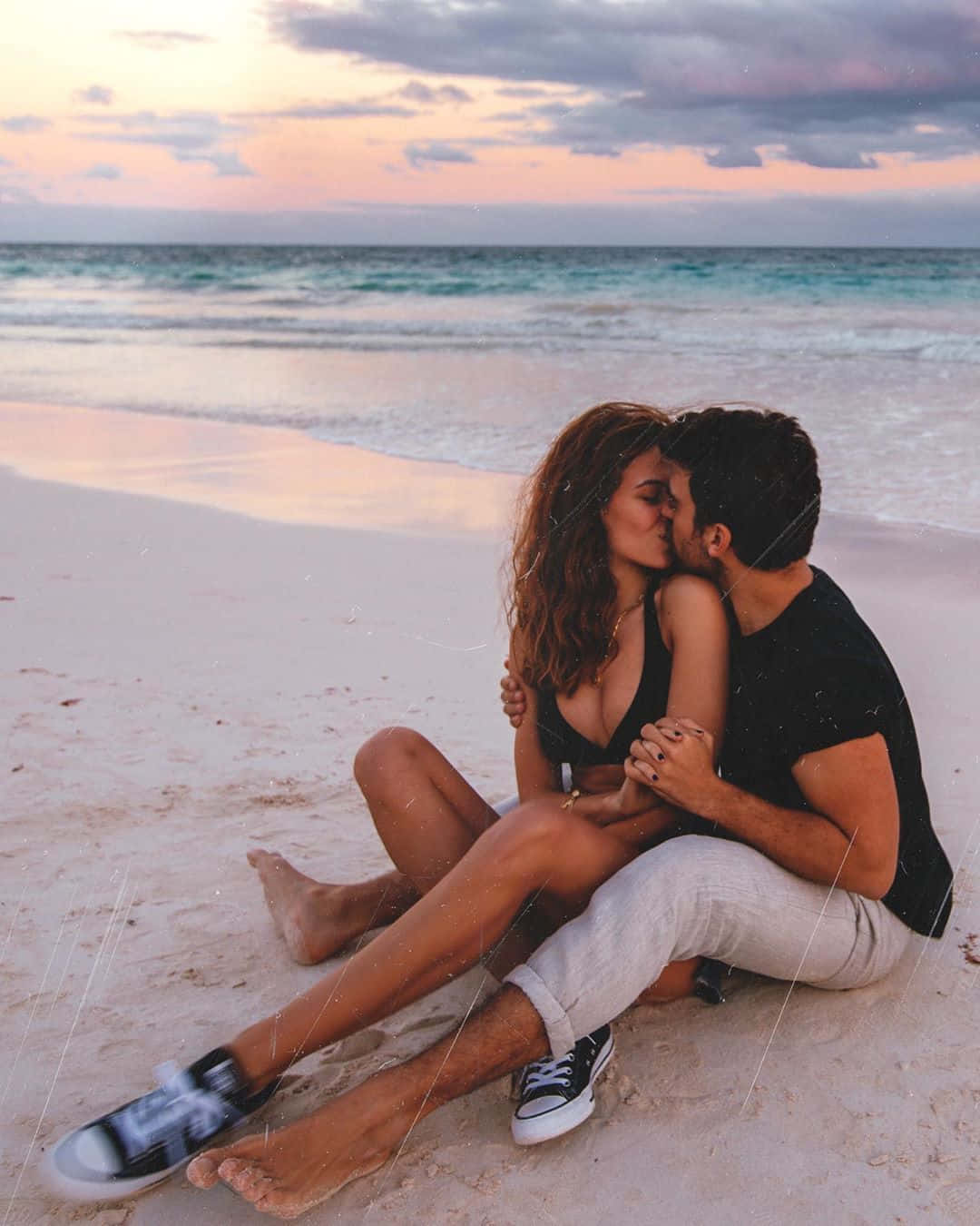 Love Unleashed: A Blissful Couple Enjoying The Beach Sunrise Background