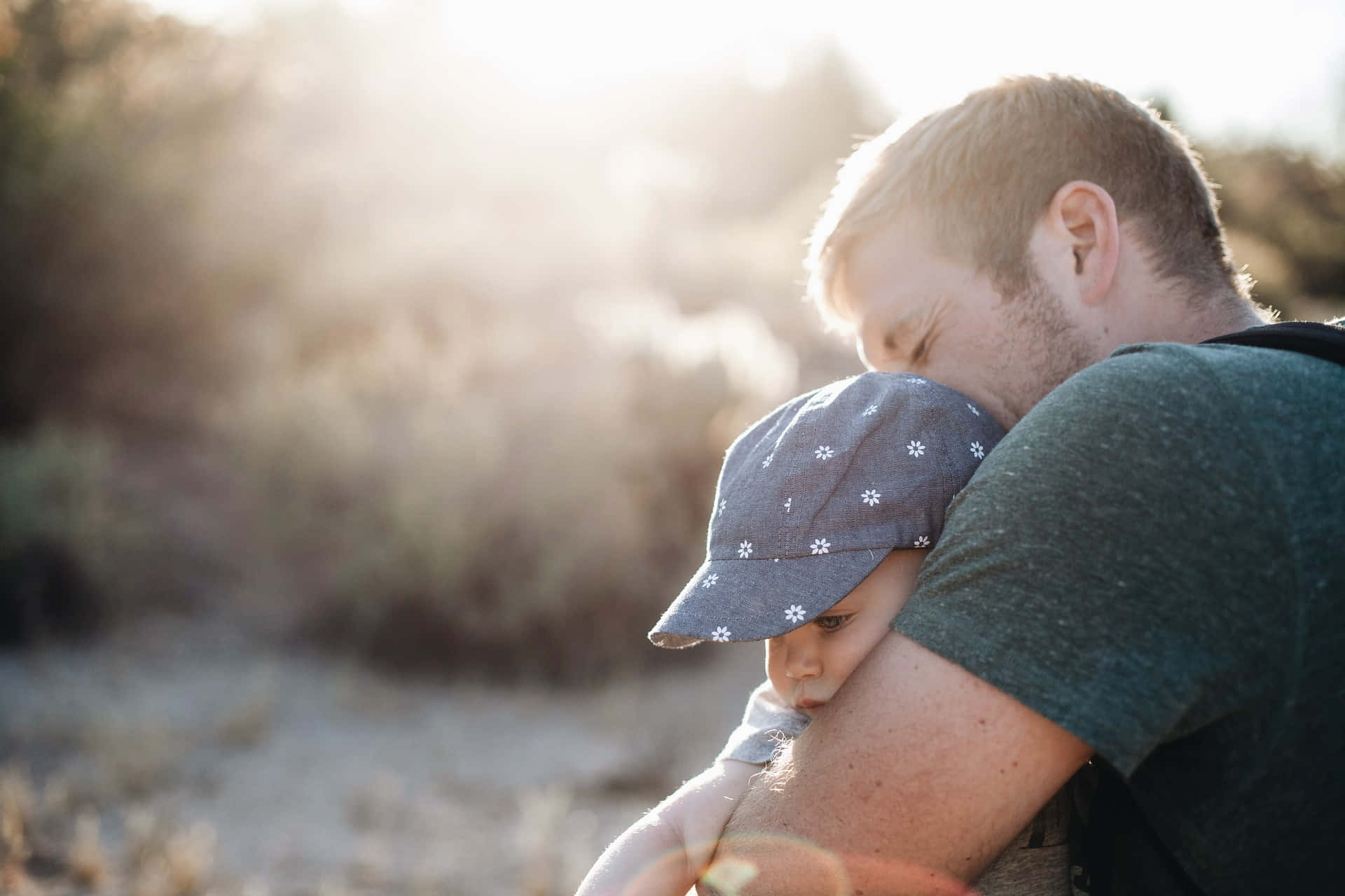 Lovely Photo Of A Father Hugging His Tangible Baby Under The Sunlight Background