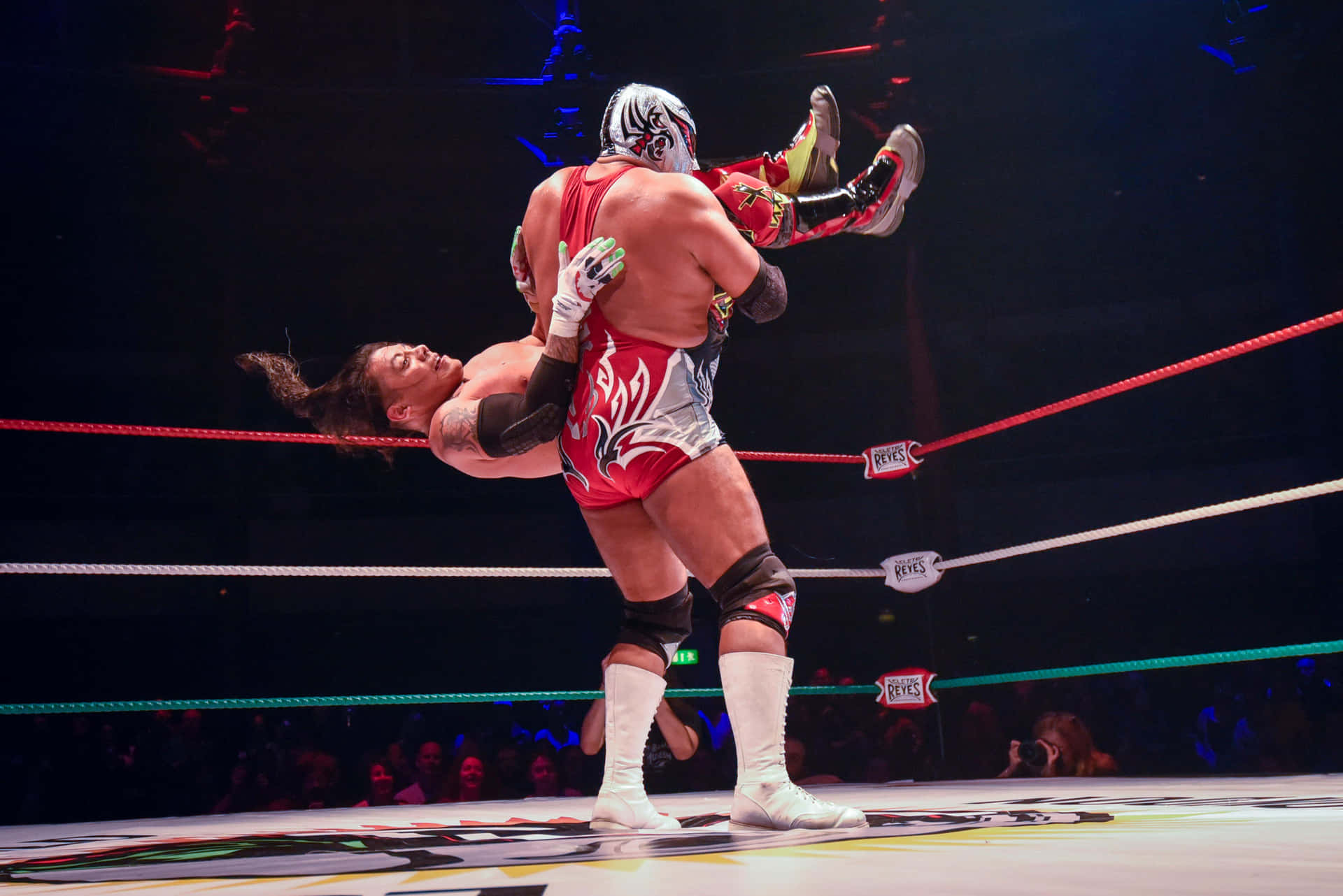 Luchador Performing Suplex Move Wrestling Match Background