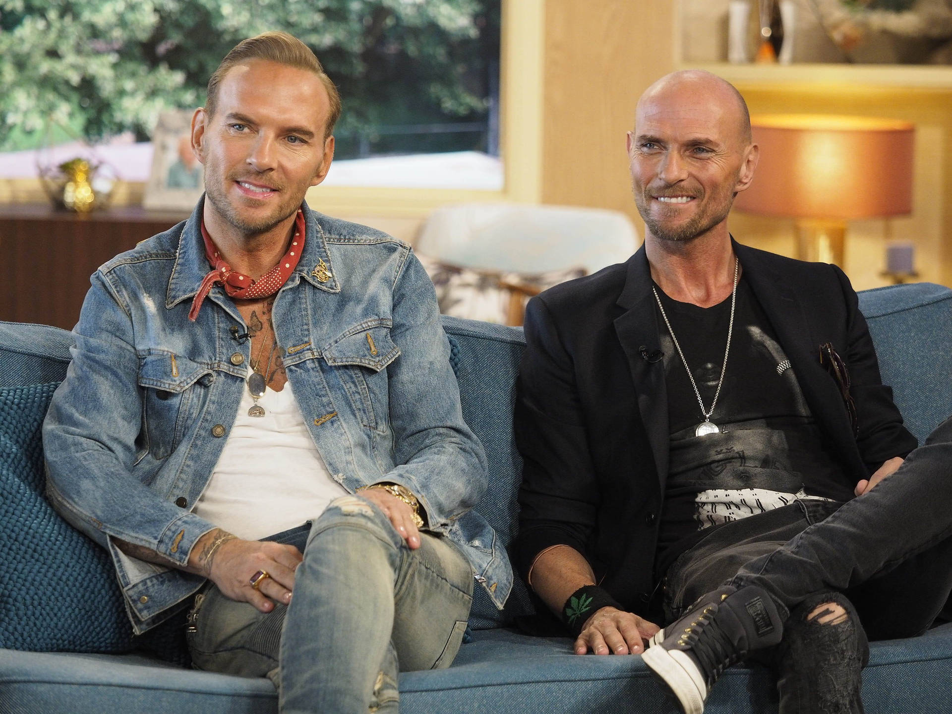 Luke Goss And Matt Goss On A Blue Couch Background