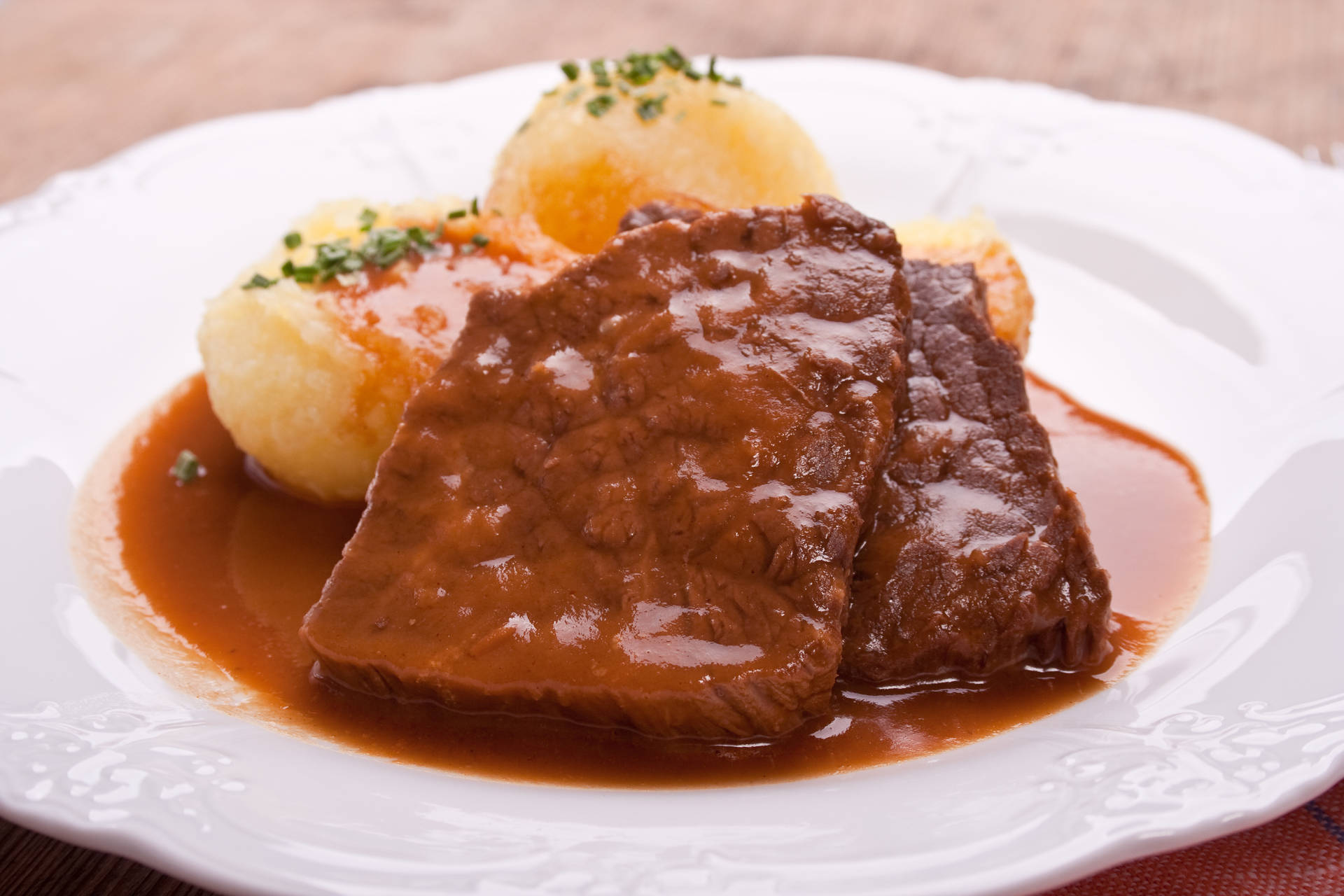 Luscious Sauerbraten Traditional German Dish With Potato Dumplings Background