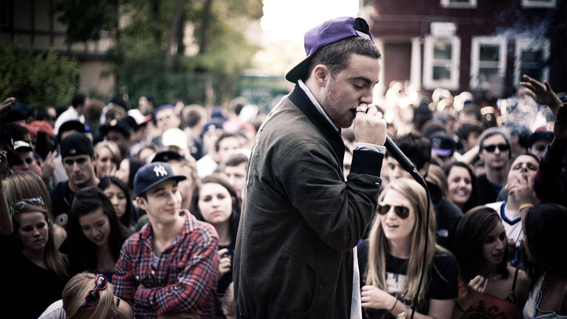 Mac Miller Performing Outdoors With Crowd Background