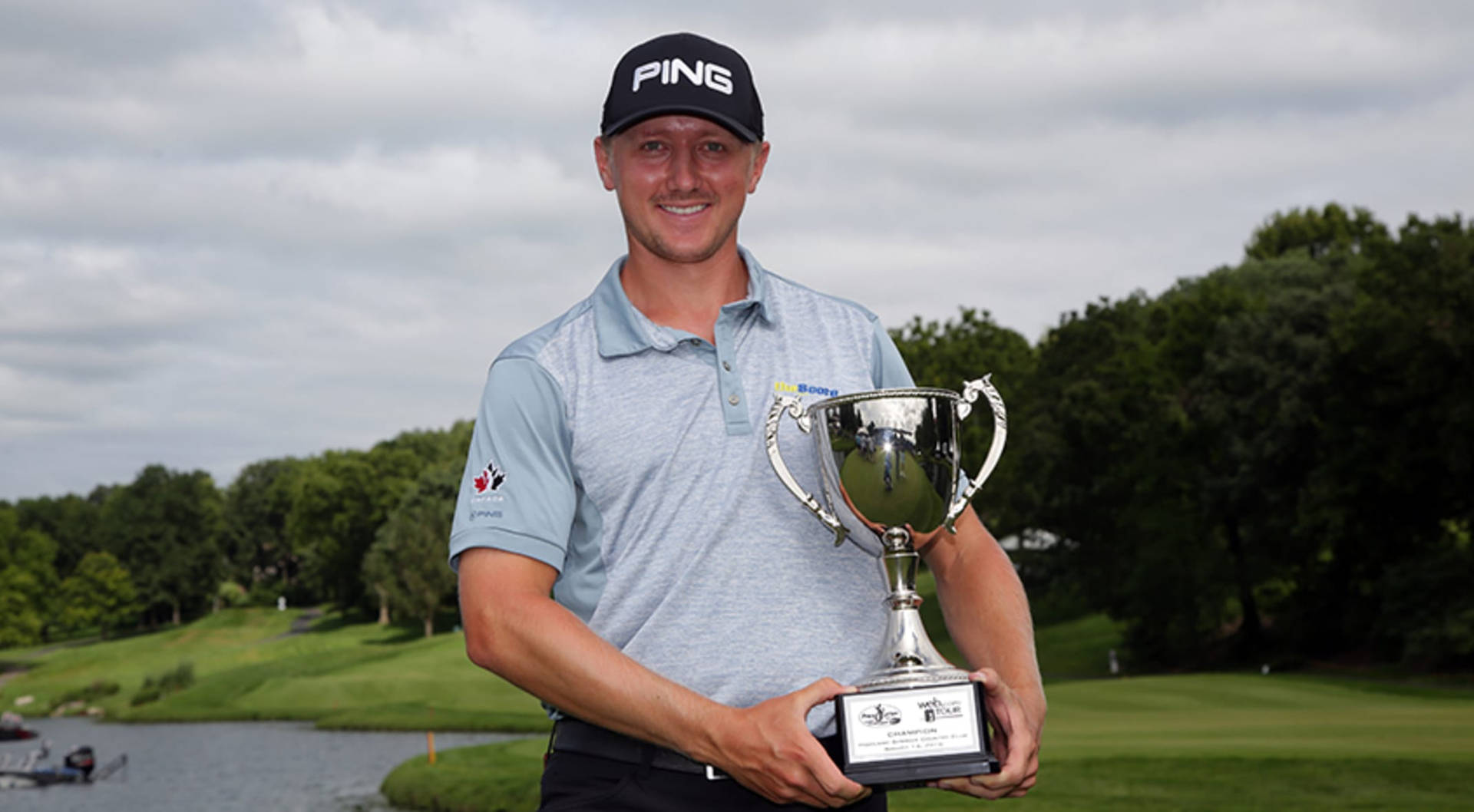 Mackenzie Hughes Smiling With Trophy Background