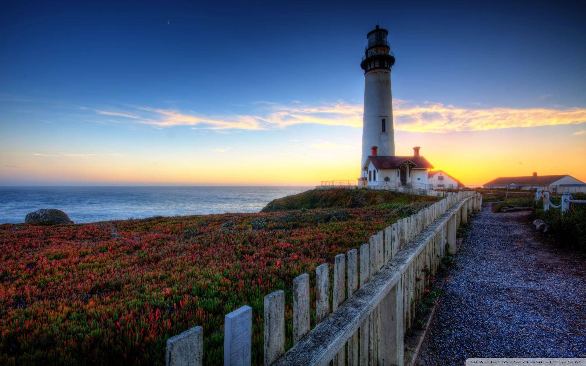 Majestic Lighthouse Illuminating The Night Sky Background