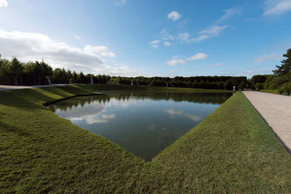 Majestic Mirror Pool Reflecting The Grandeur Of The Palace Of Versailles Background