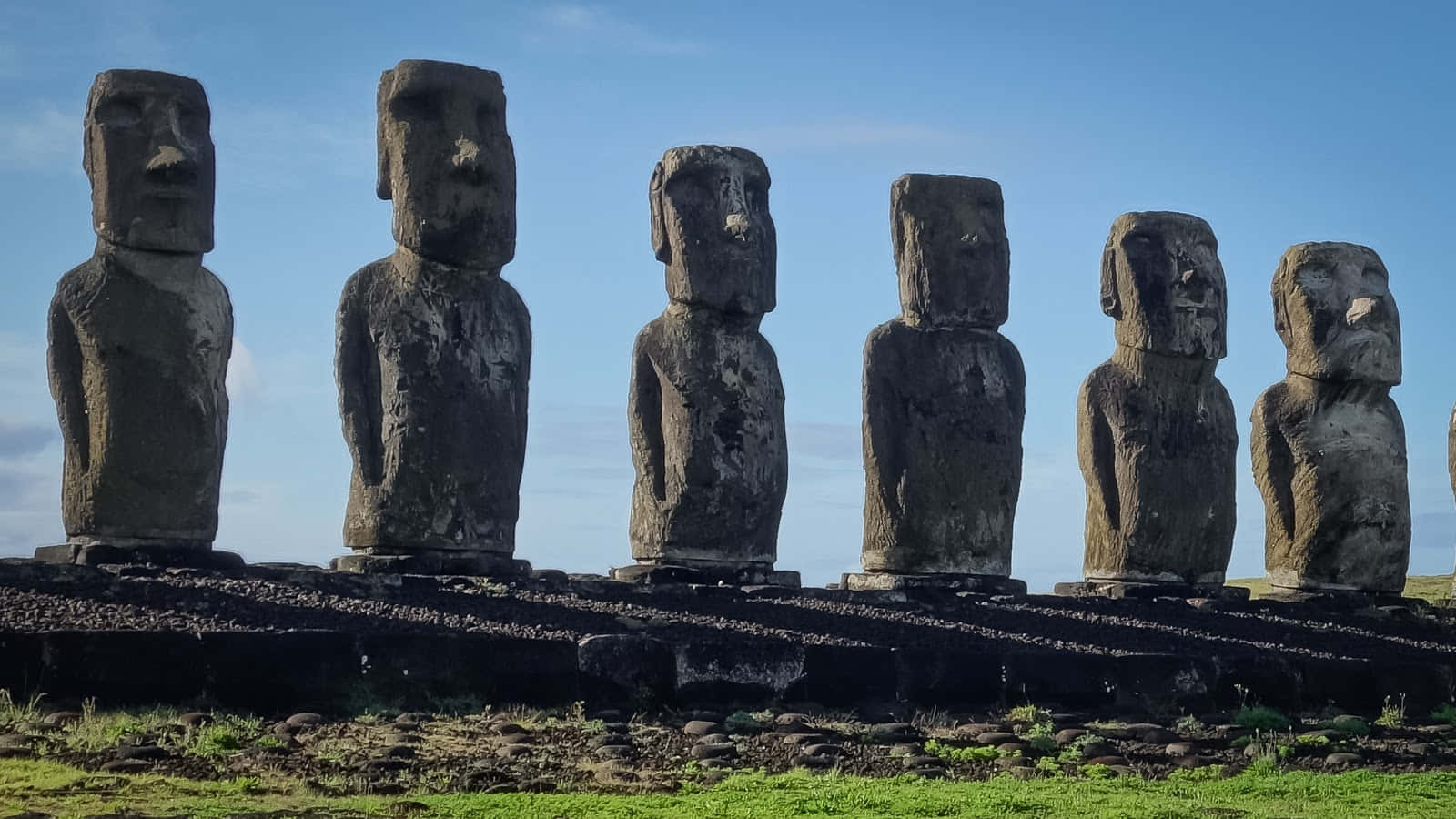 Majestic Moai Statues Cast Shadows At Sunset Background