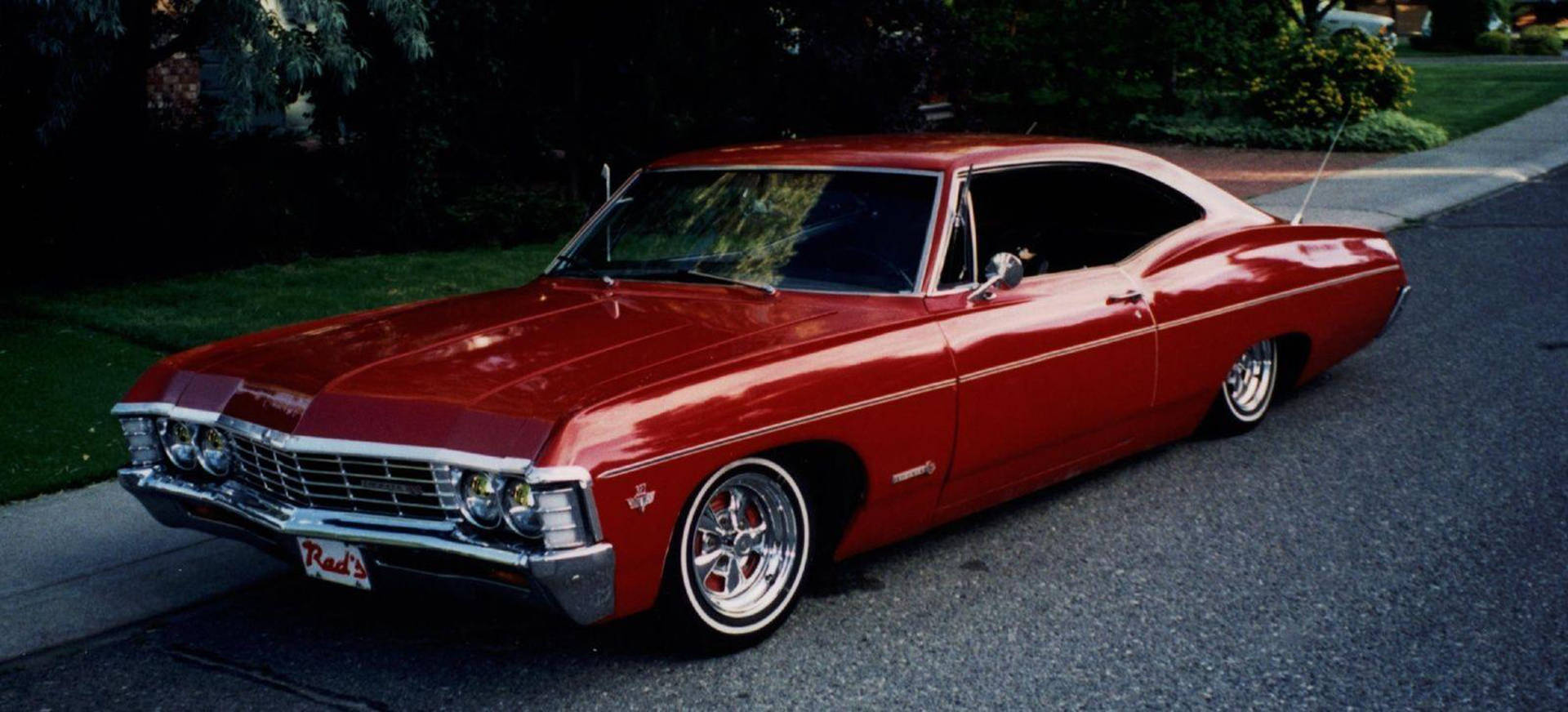 Majestic Red 1967 Chevrolet Impala Showcasing Vintage Beauty Background