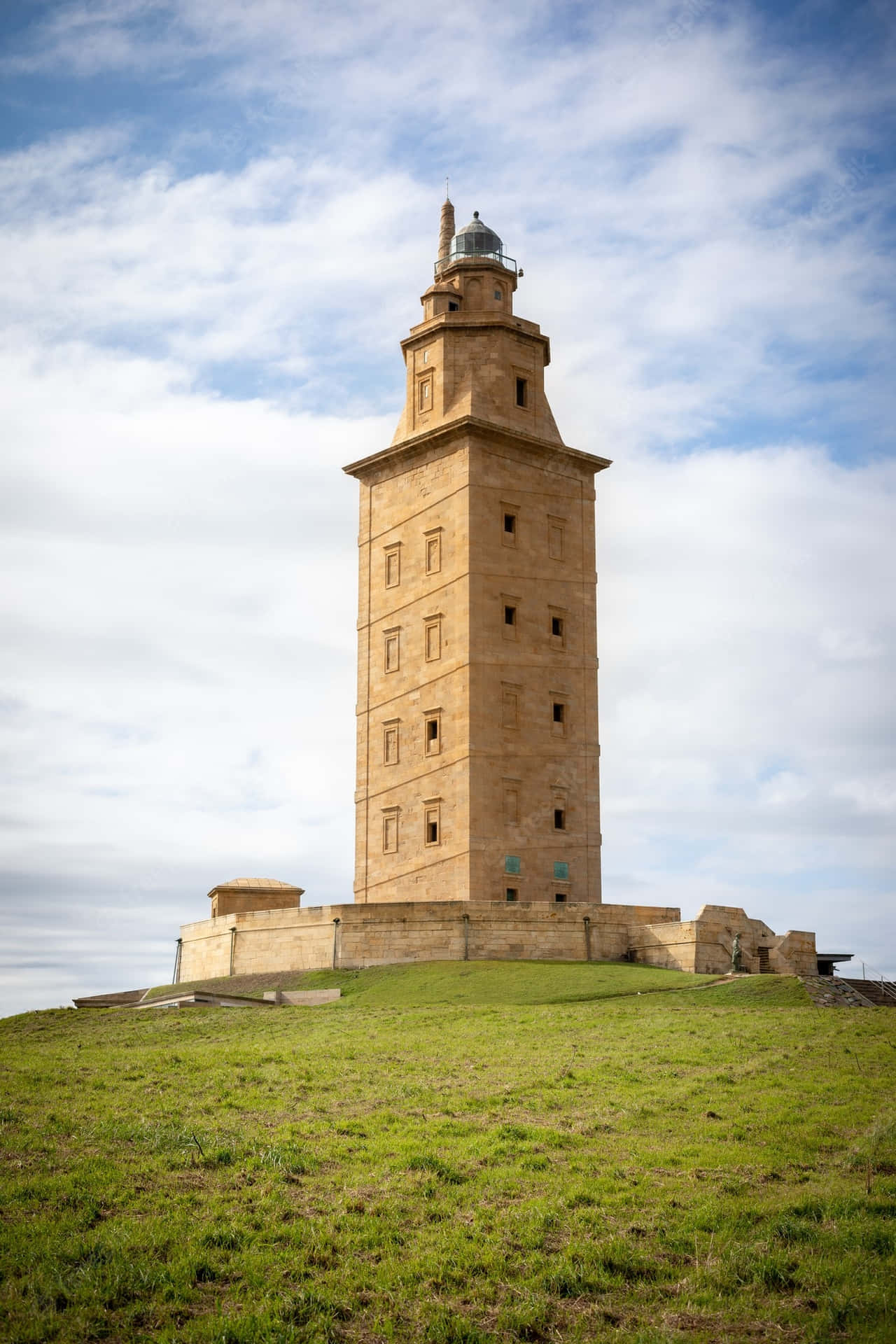 Majestic Tower Of Hercules Piercing The Blue Sky Background