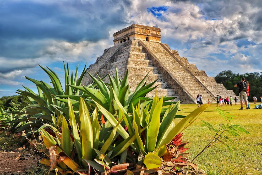 Majestic View Of Ancient Chichen Itza Pyramid Surrounded By Lush Foliage Background