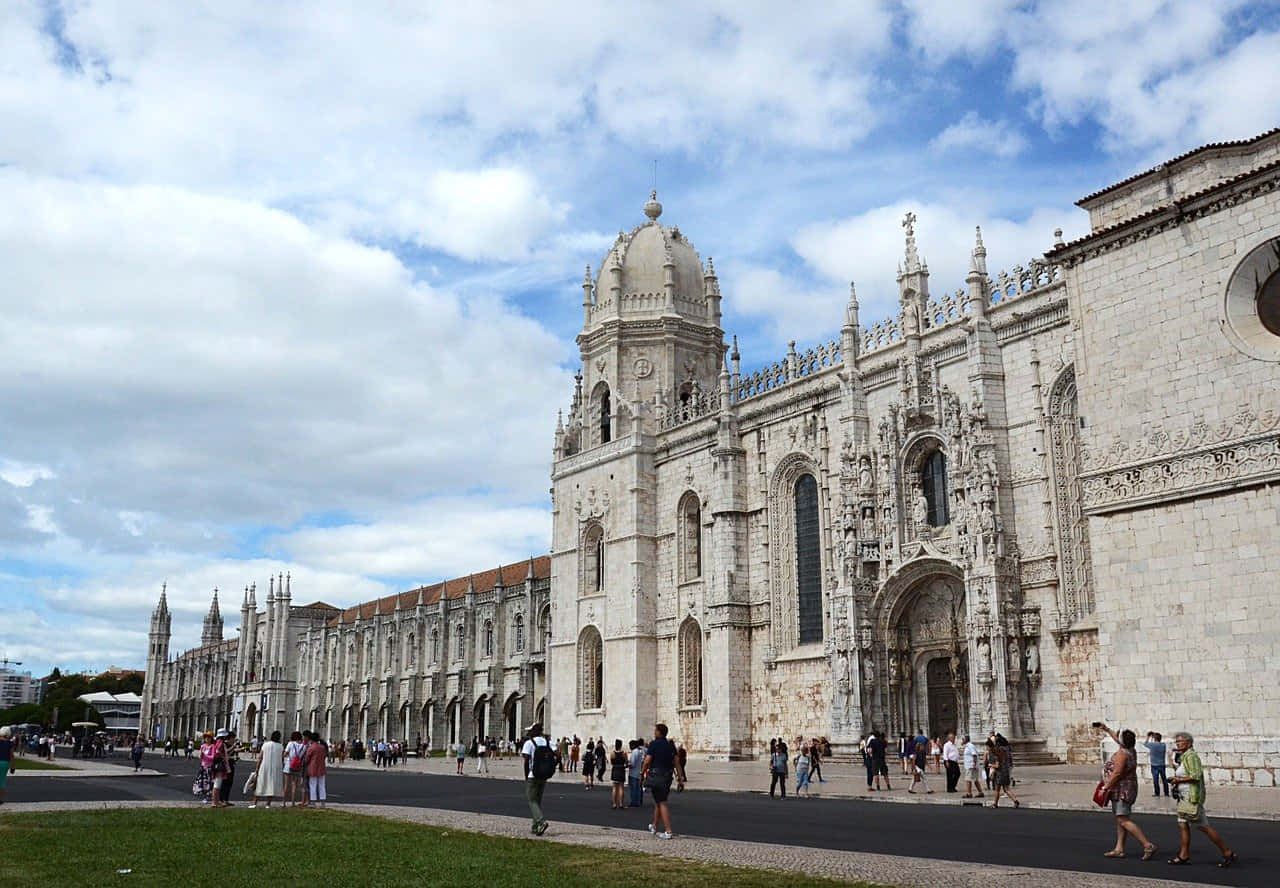 Majestic View Of The Front Exterior Of Mosteiro Dos Jeronimos In Lisbon, Portugal. Background