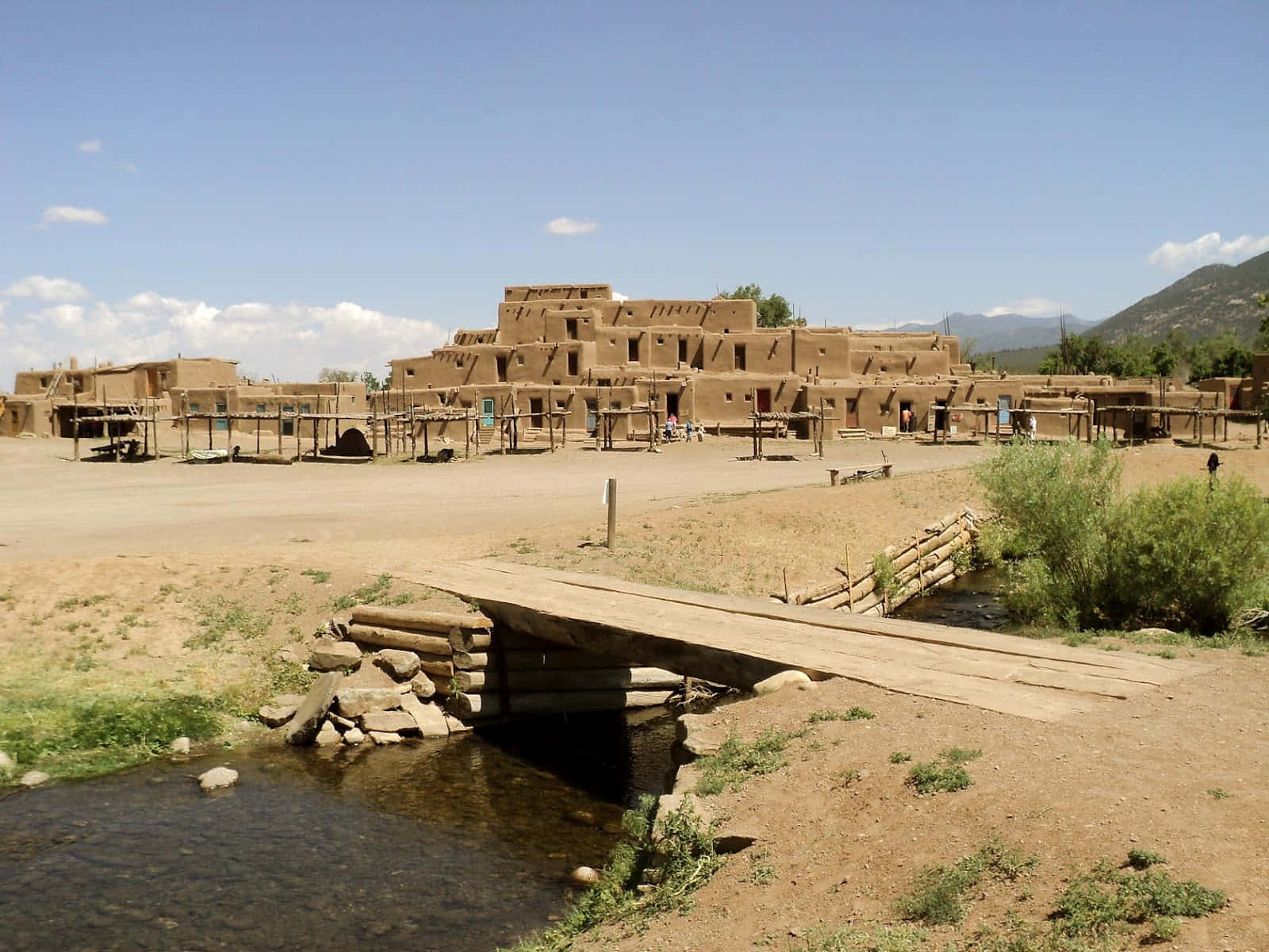 Makeshift Bridge Over Taos Pueblo River Background