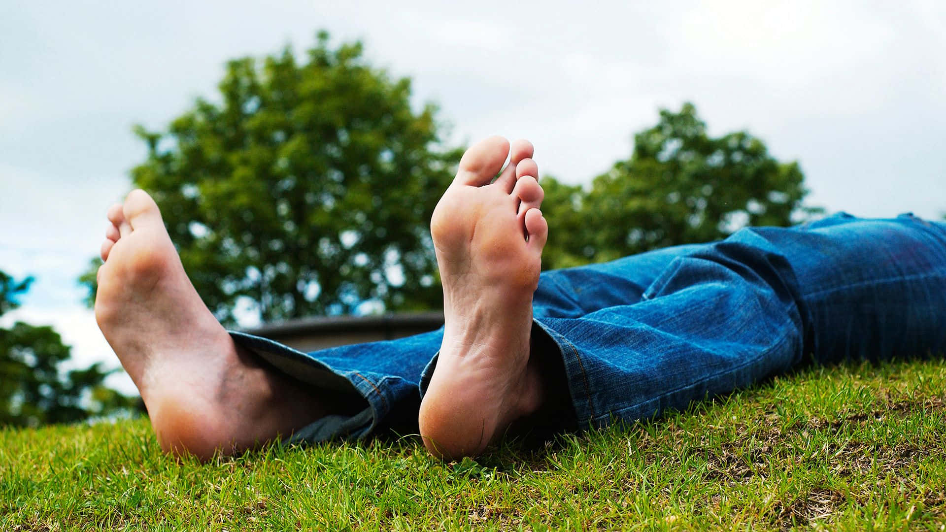 Male Lying On The Grass Showing Bare Feet Background