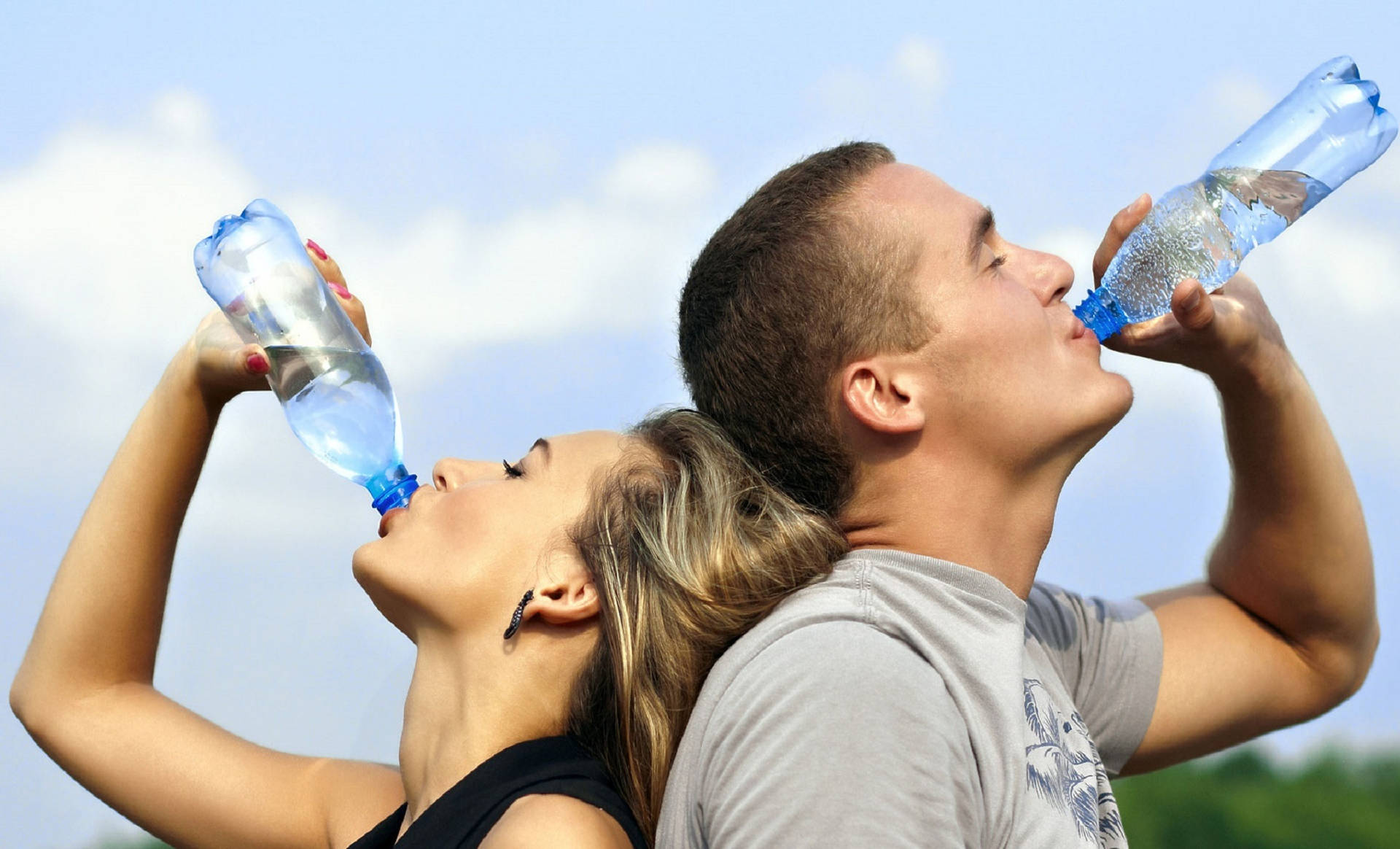 Man And Woman Drinking Water From Bottles