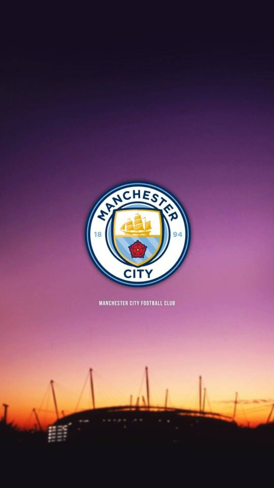 Man City’s Logo Illuminated Against A Magnificent Purple Sky Background