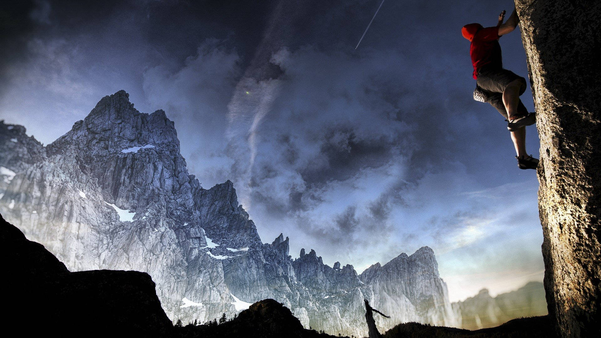 Man Climbing A Rock Overlooking Icy Mountains Background