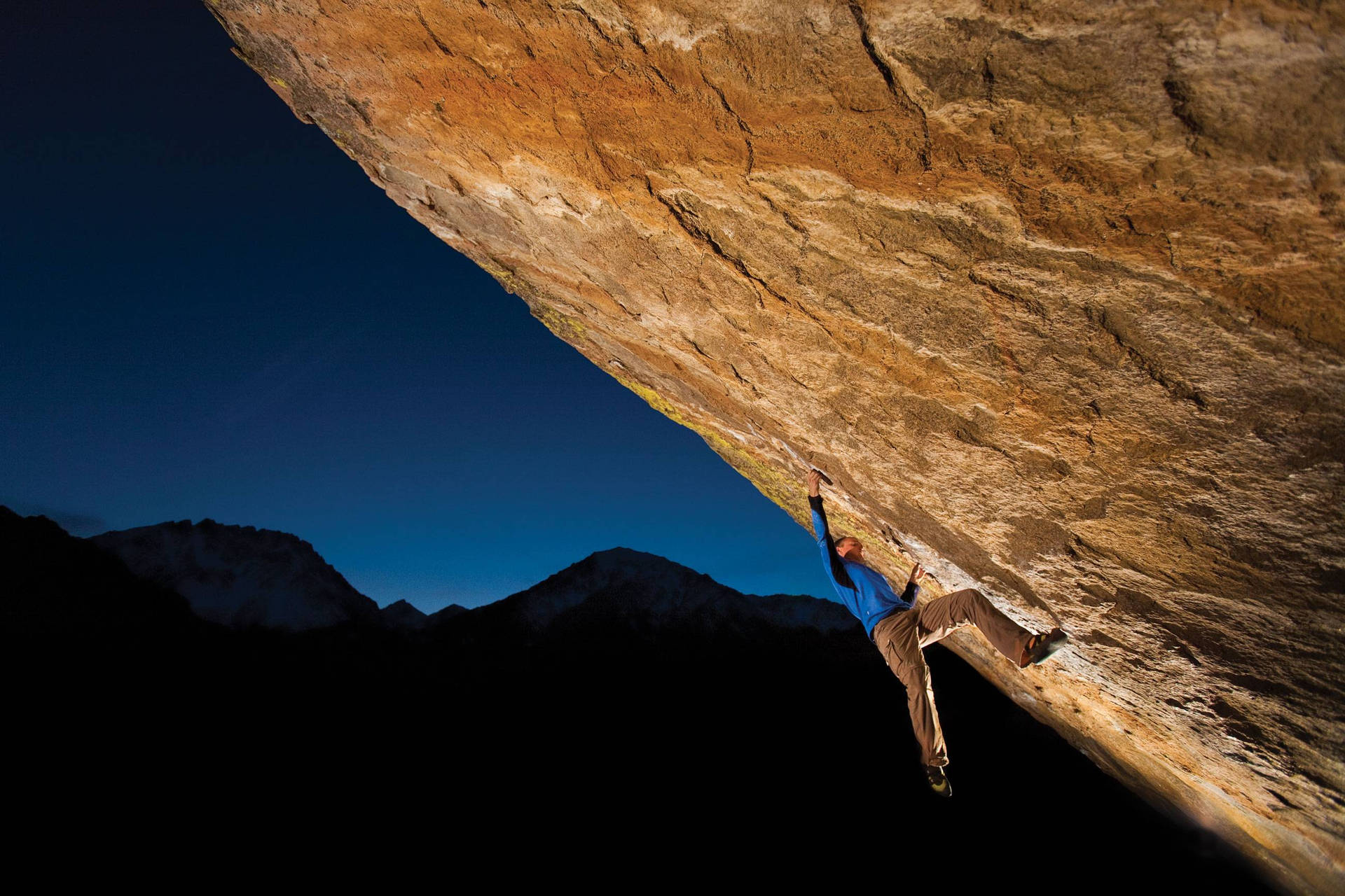 Man Conquering Heights: Nighttime Rock Climbing Background