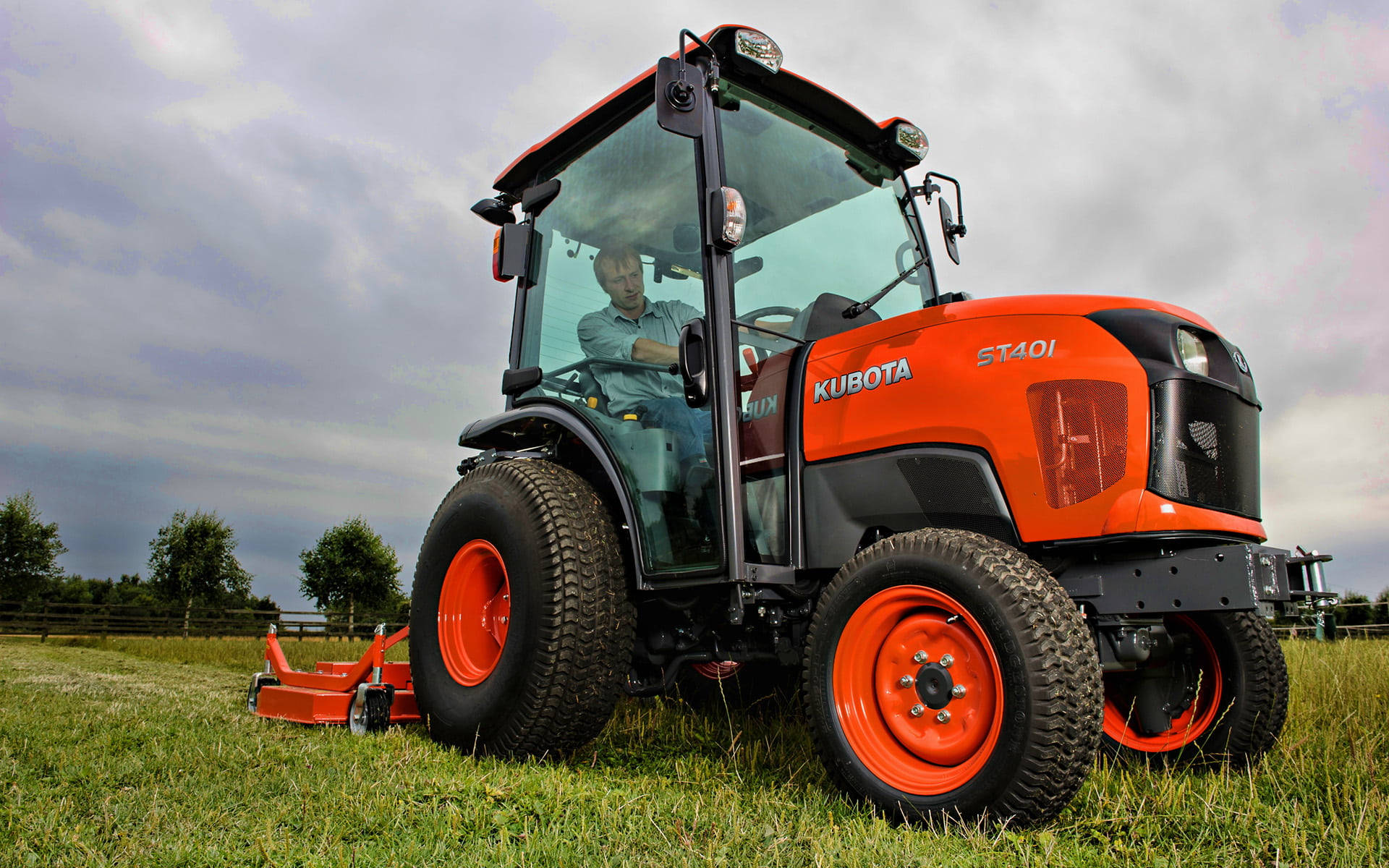 Man Driving Orange Kubota Tractor Background