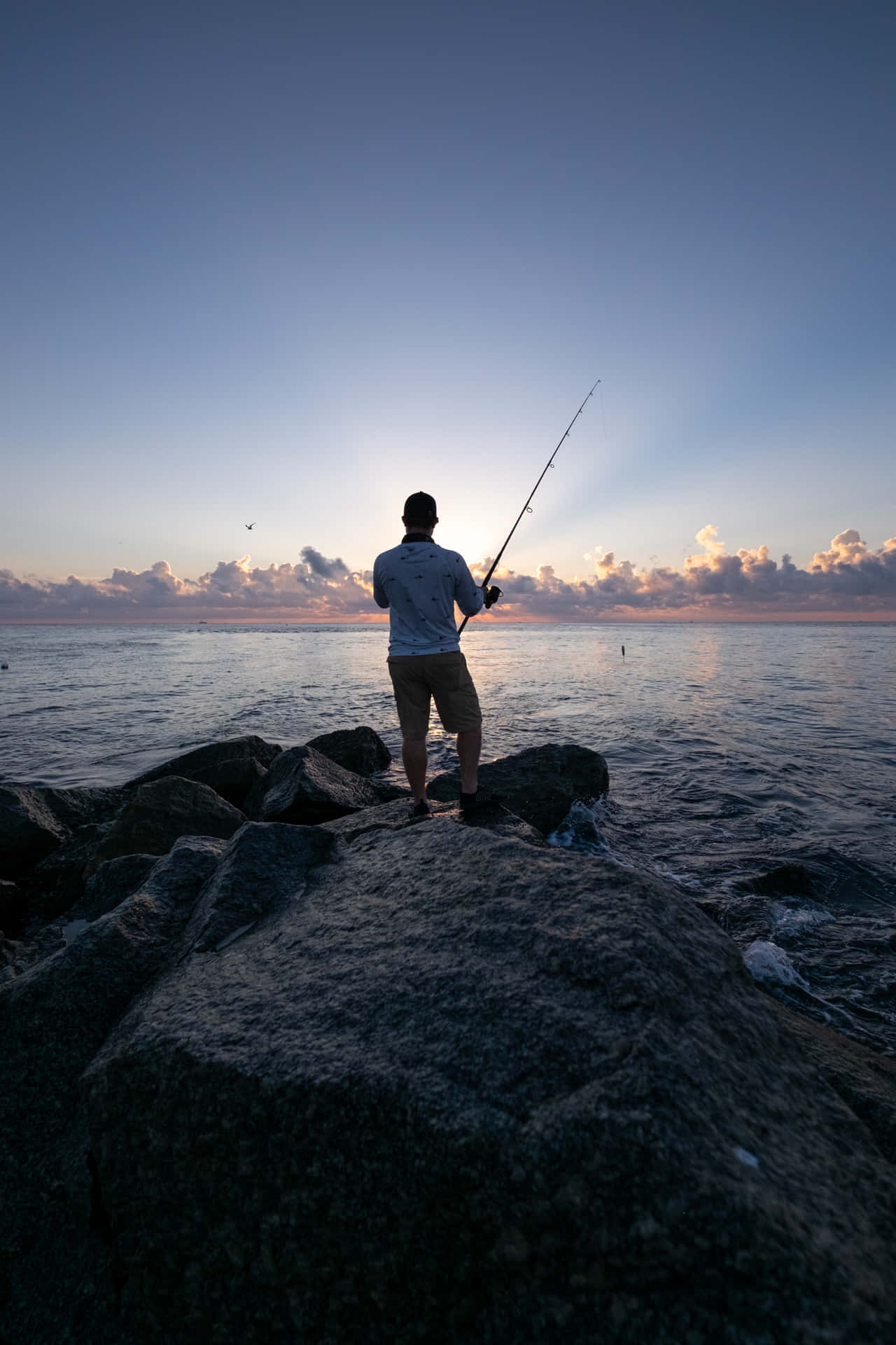 Man Fishing By The Lake Using His Phone
