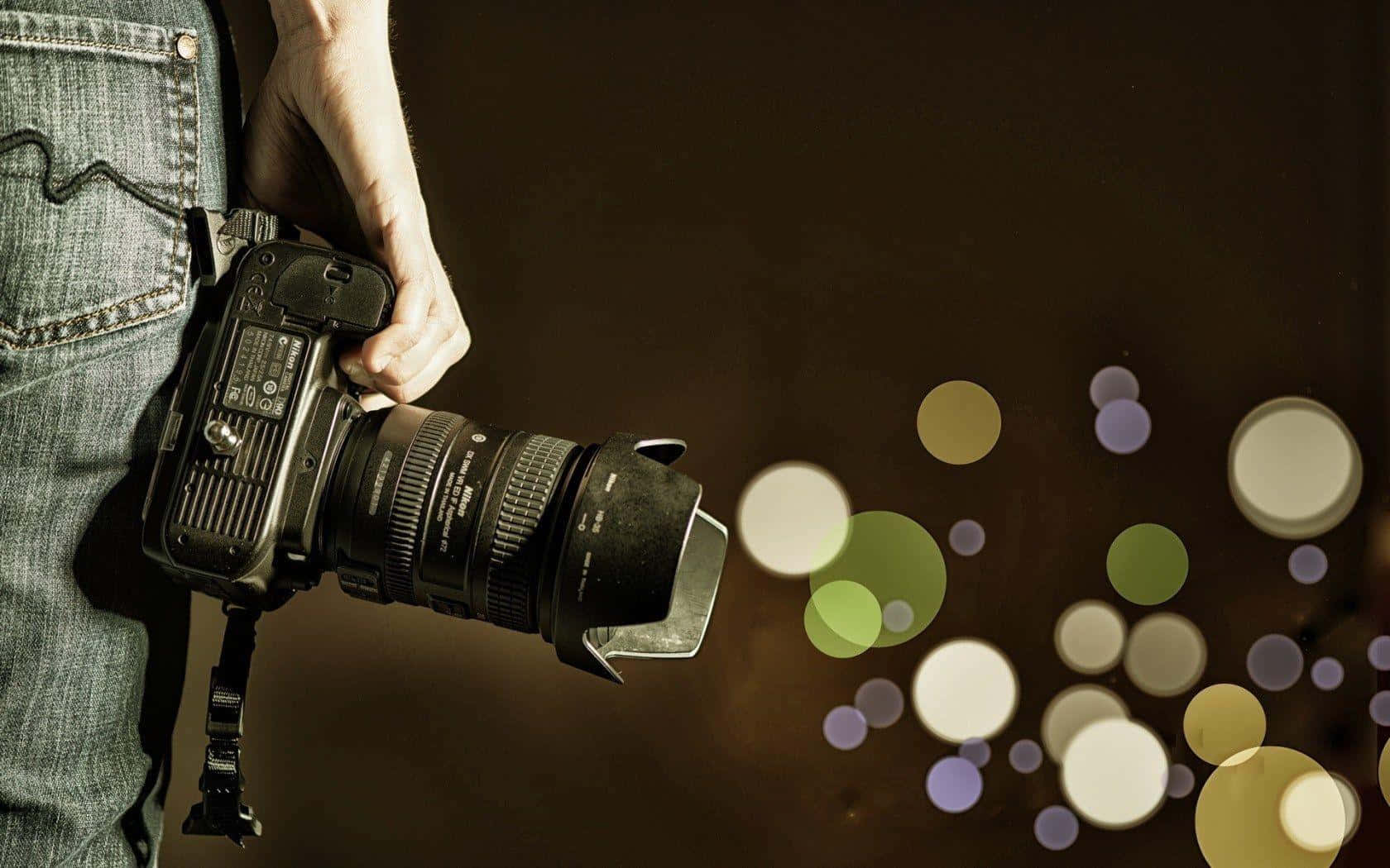Man Holding Photography Camera On Blurred Light Background