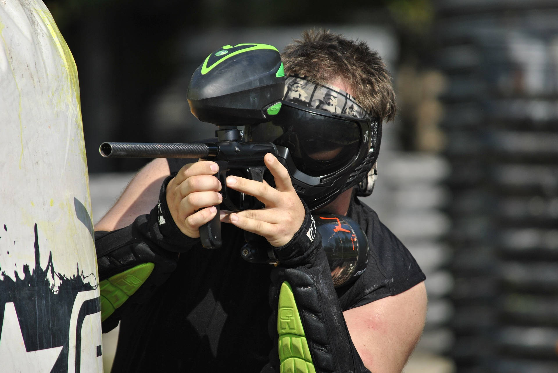 Man In Green Elbow Pads Shooting Paintball Background