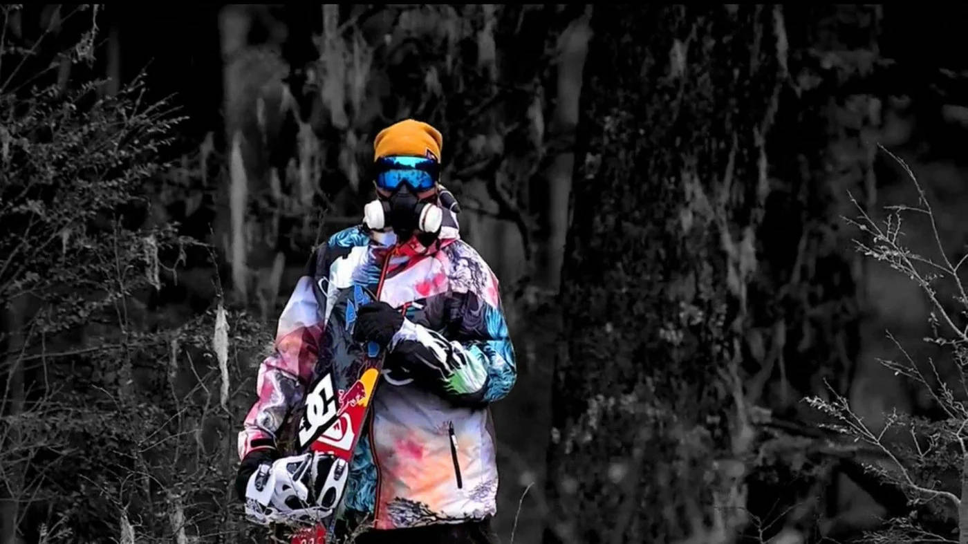 Man In Multi-colored Outfit With Snowboard Background