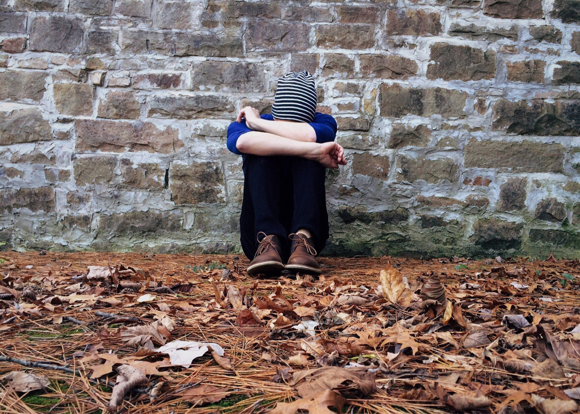 Man Sitting Alone Against Brick Wall Background