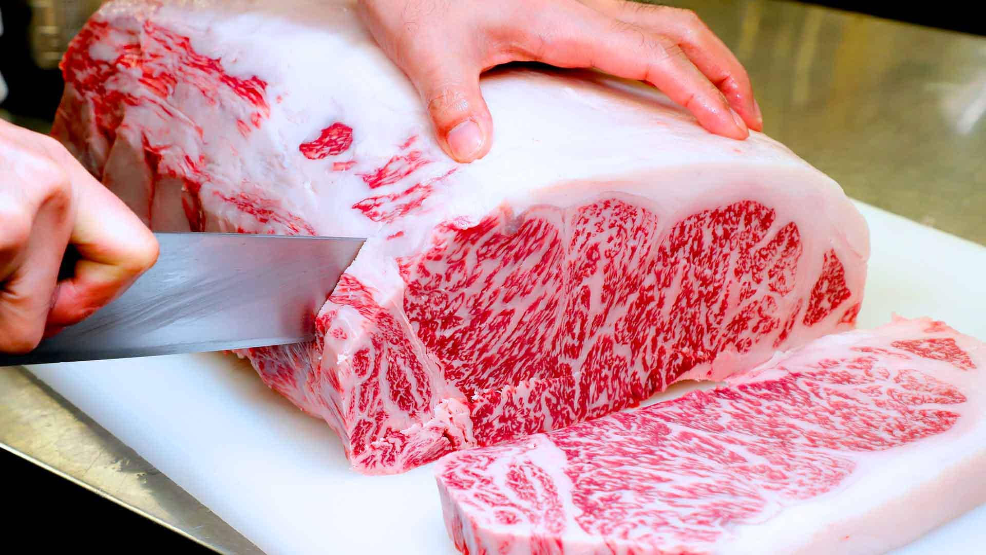 Man Slicing Sizeable Chunk Of Kobe Beef Background